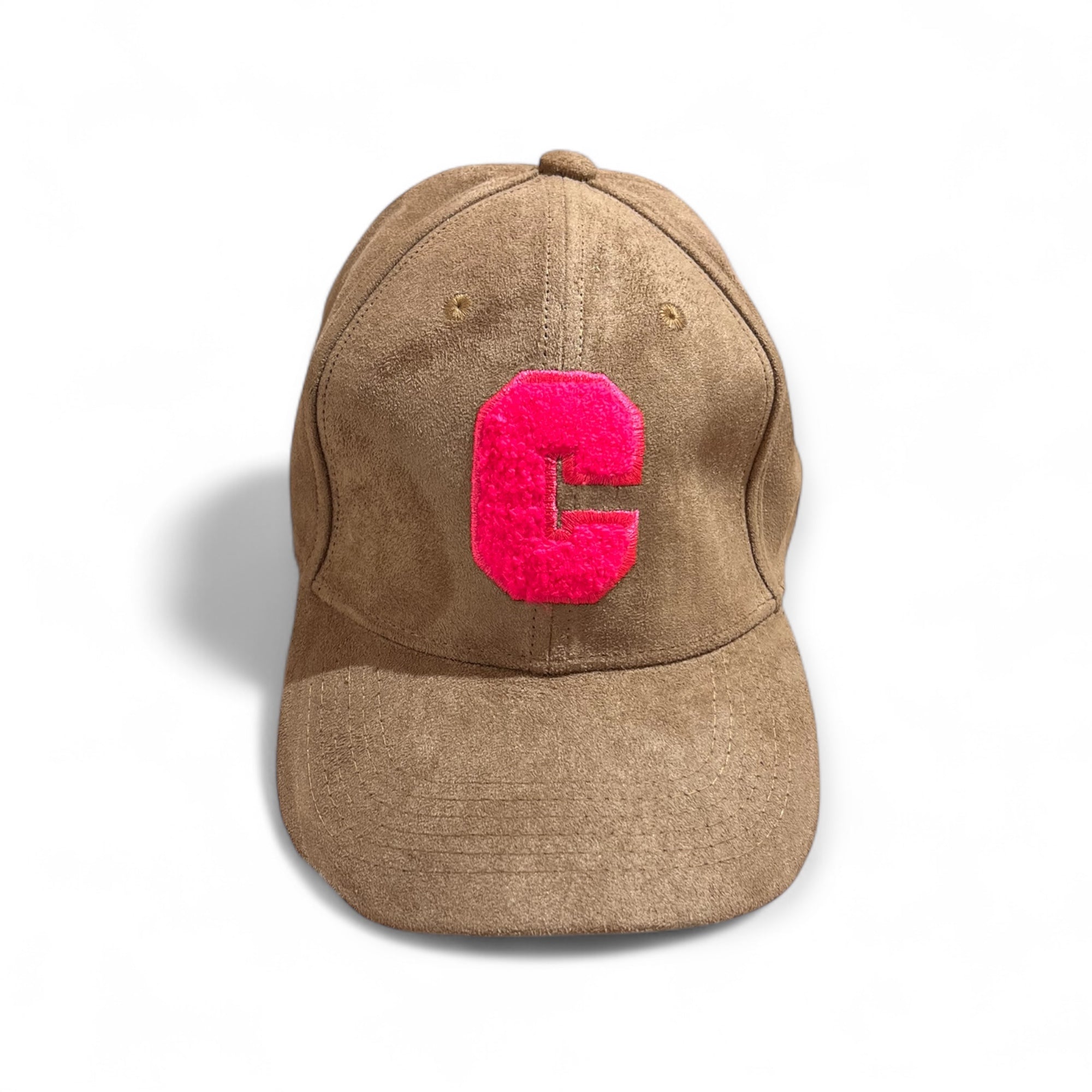 Karamellfarbene Velours-Cap mit großem pinkem Buchstaben C auf der Vorderseite, fotografiert auf weißem Hintergrund.