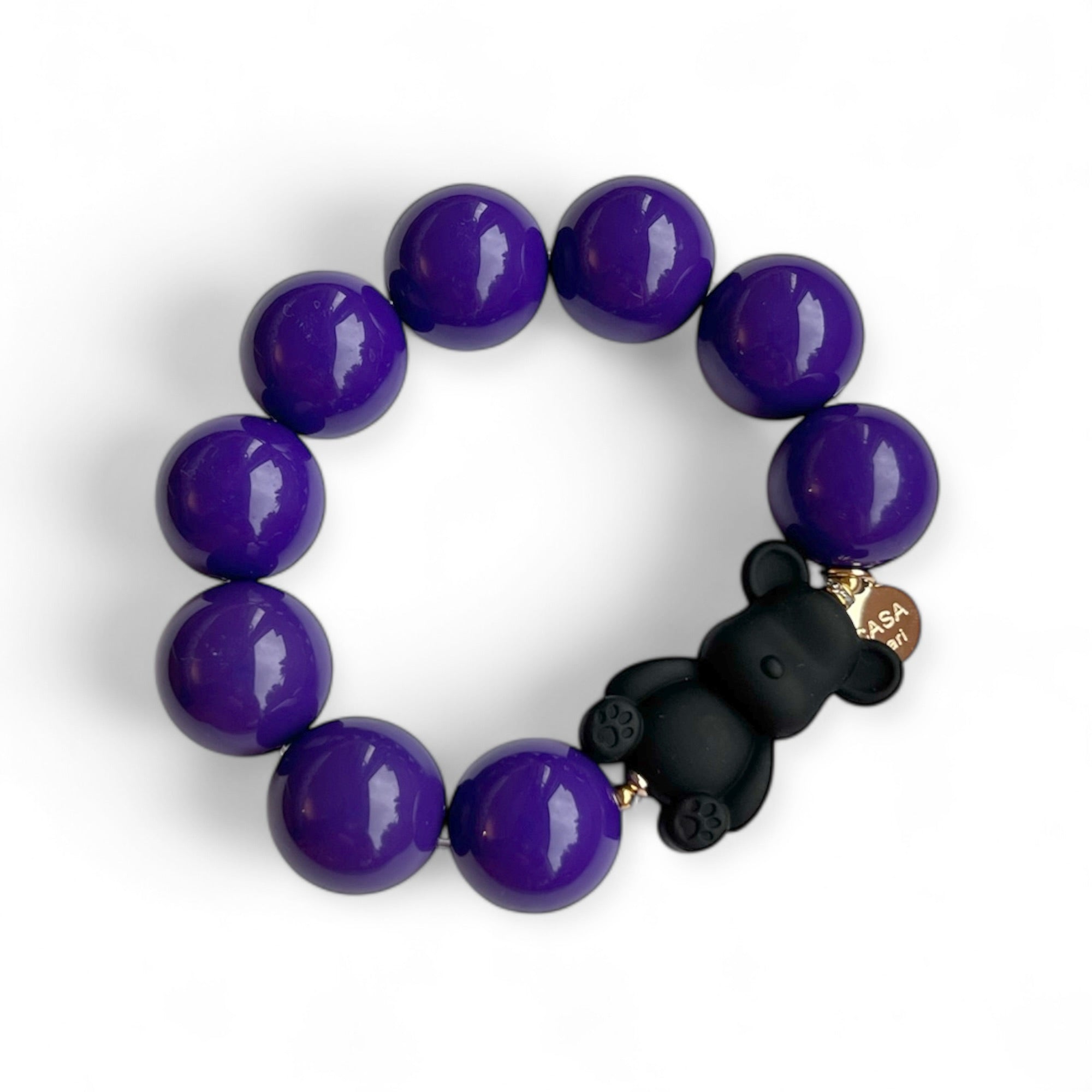 Armband aus lilafarbenen Kunstharzperlen mit einem kleinen schwarzen Bärenelement, handgefertigt von Casapari auf weißem Hintergrund.
