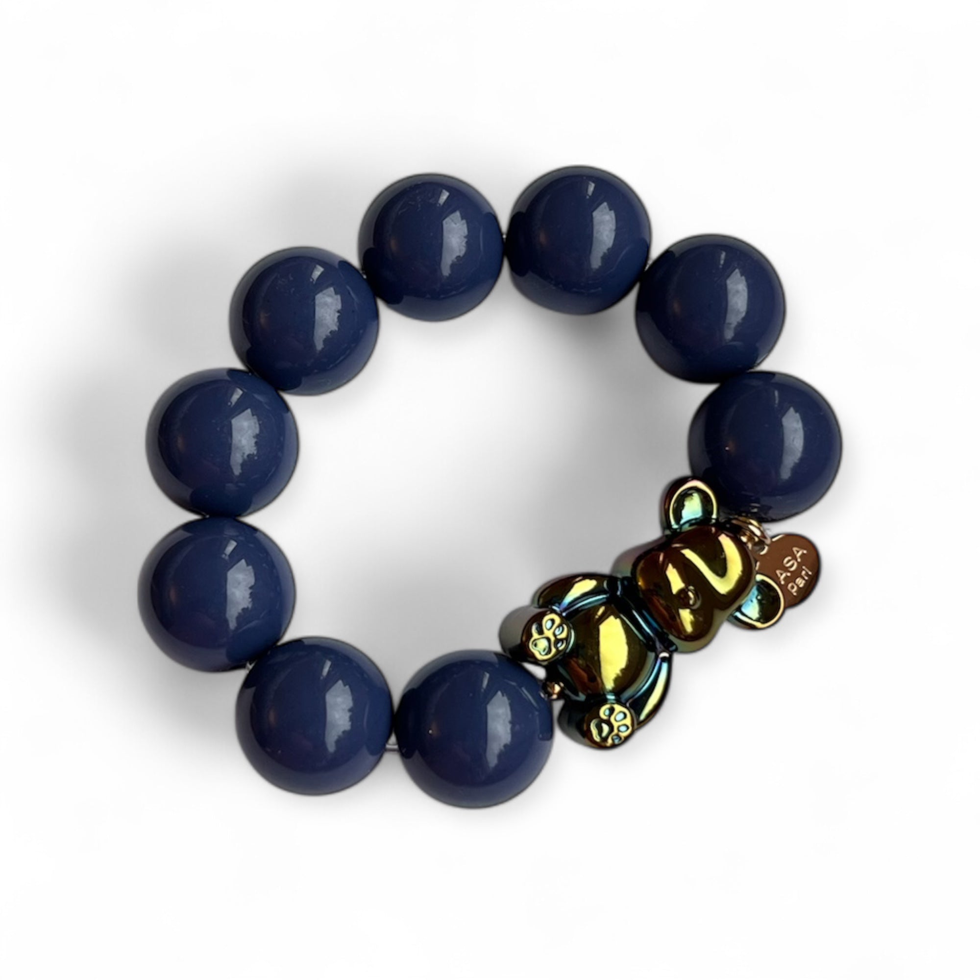 Armband aus blauen Kunstharzperlen mit einem kleinen schimmernden Bärenelement, handgefertigt von Casapari auf weißem Hintergrund.