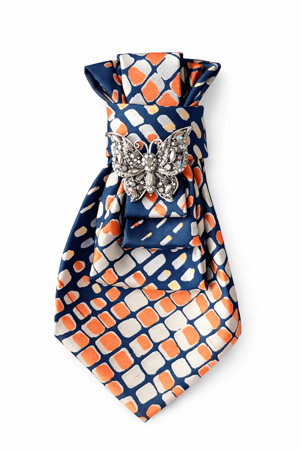 Dunkelblaue, gemusterte Krawatte mit geometrischem Muster in Orange und Creme, mittig gefaltet und mit einer silberfarbenen Schmetterlingsbrosche mit Strasssteinen fixiert, freigestellt vor hellem Hintergrund.