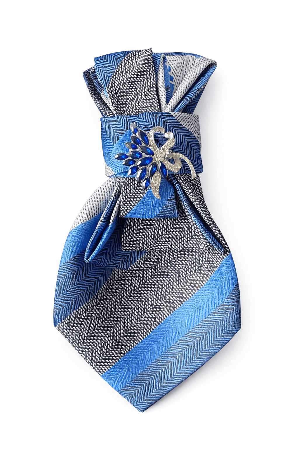 Blau gemusterte Seidenkrawatte, dekorativ gefaltet, mit einer silberfarbenen Brosche mit blauen Steinen in der Mitte.
Die Krawatte zeigt verschiedene geometrische Muster in Blau, Schwarz und Weiß.