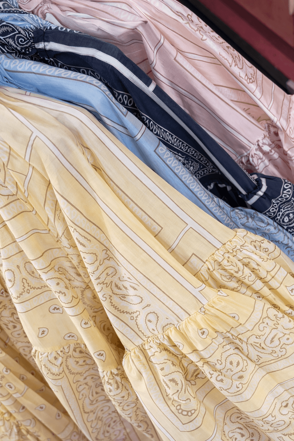 Leicht fallender Stoff mit Paisley-Muster in Gelb, Hellblau und Dunkelblau, mit gerafftem Bund und weichen Falten.