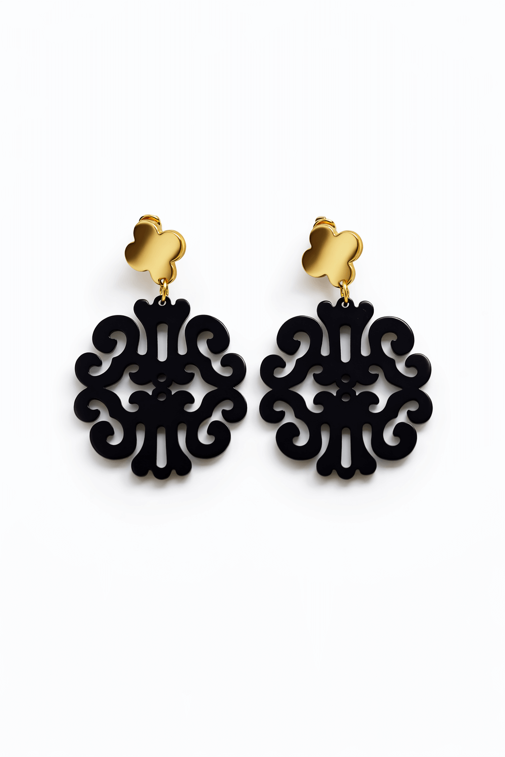 Paar hängende Ohrringe mit goldfarbenem Kleeblatt-Stecker und schwarzem, ornamental durchbrochenem Anhänger vor weißem Hintergrund.