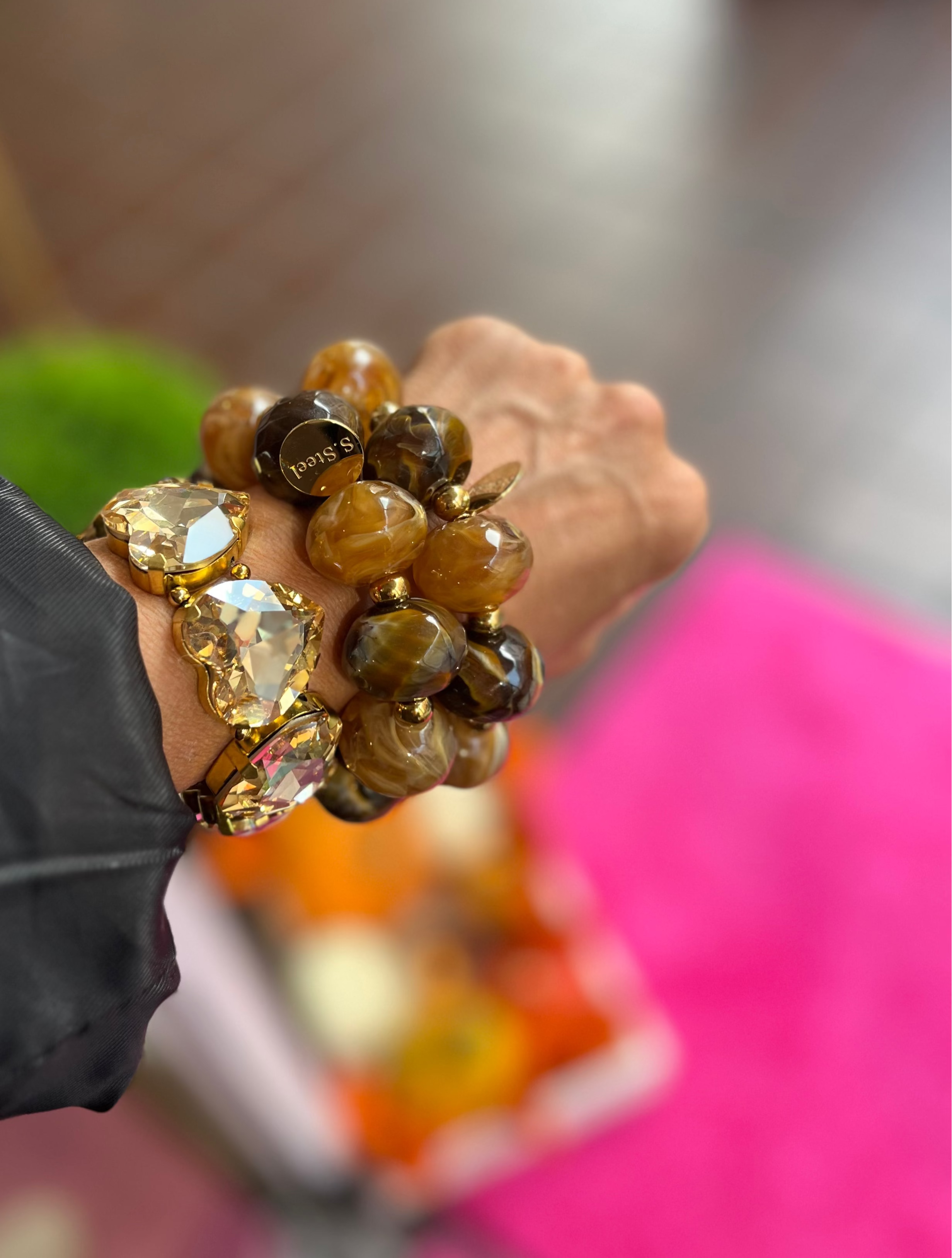 Handgelenk mit drei Armbändern. Zwei Kunstharz Armbänder in Braun Beige Tönen und ein funkelndes goldfarbenes Crystal Armband. 