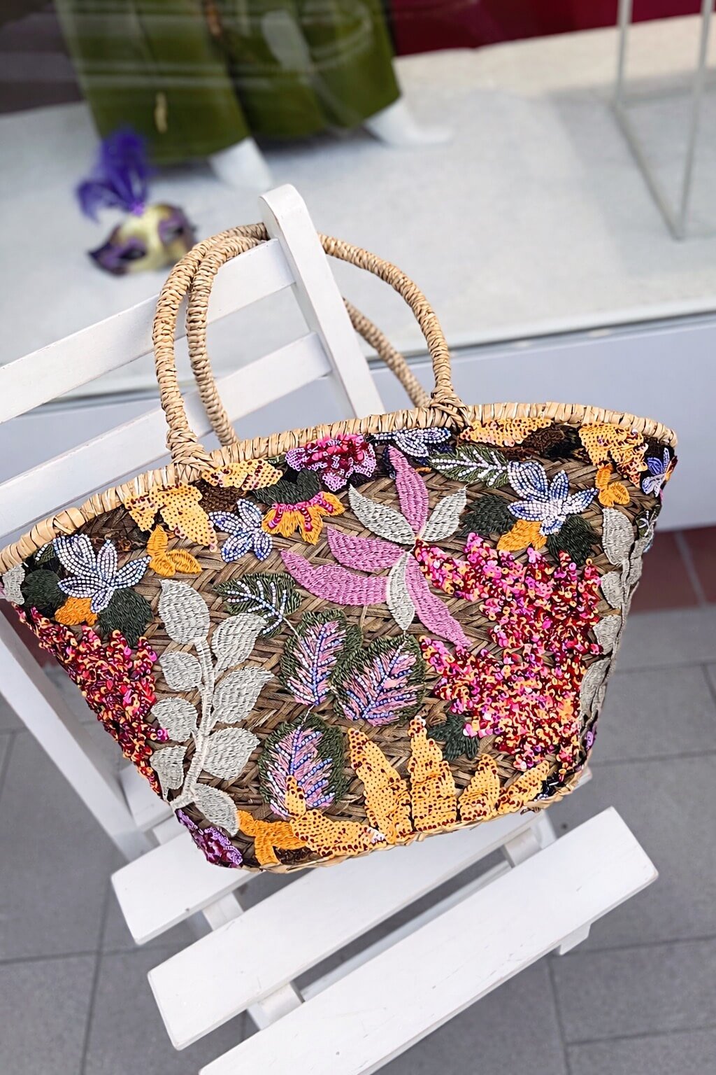 Handgeflochtene Basttasche mit zwei runden Tragehenkeln, überzogen mit transparentem Stoff und aufwendig applizierten, schimmernden Pailletten in Gelb, Pink, Rosé, Creme und Grüntönen in floralen Mustern.