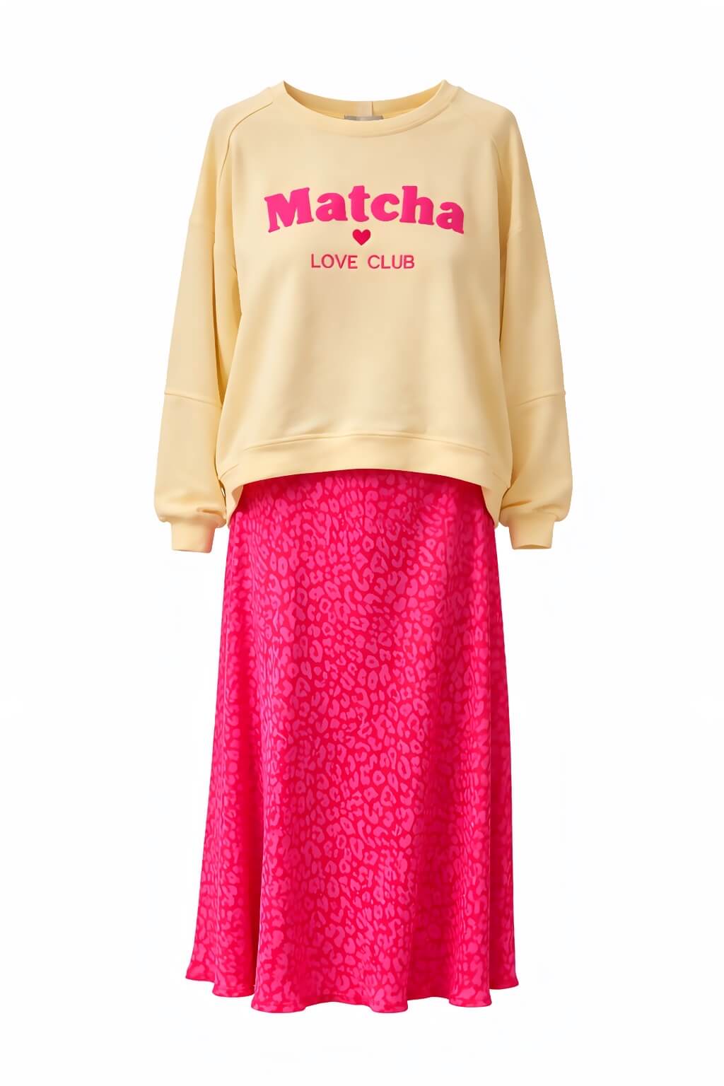 Pinkfarbener Midi-Rock mit Leo-Muster aus fließendem Stoff, kombiniert mit gelbem Sweater mit der Aufschrift „Matcha Love Club“, freigestellt vor hellem Hintergrund.