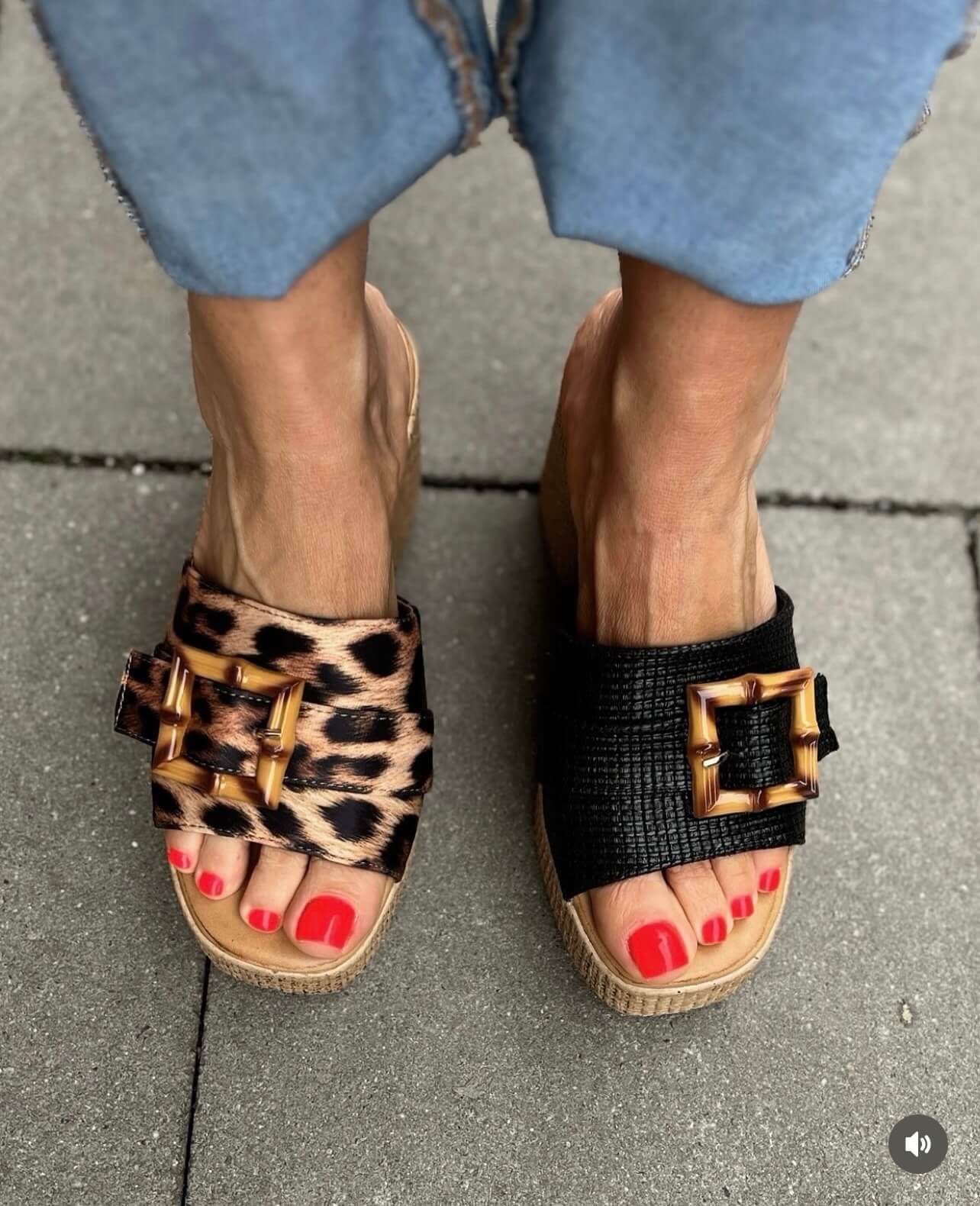 Zwei Plateau-Sandalen mit Bambus-Schnallen, einmal im Leo-Print und einmal in Schwarz, getragen zu hellblauer Jeans.