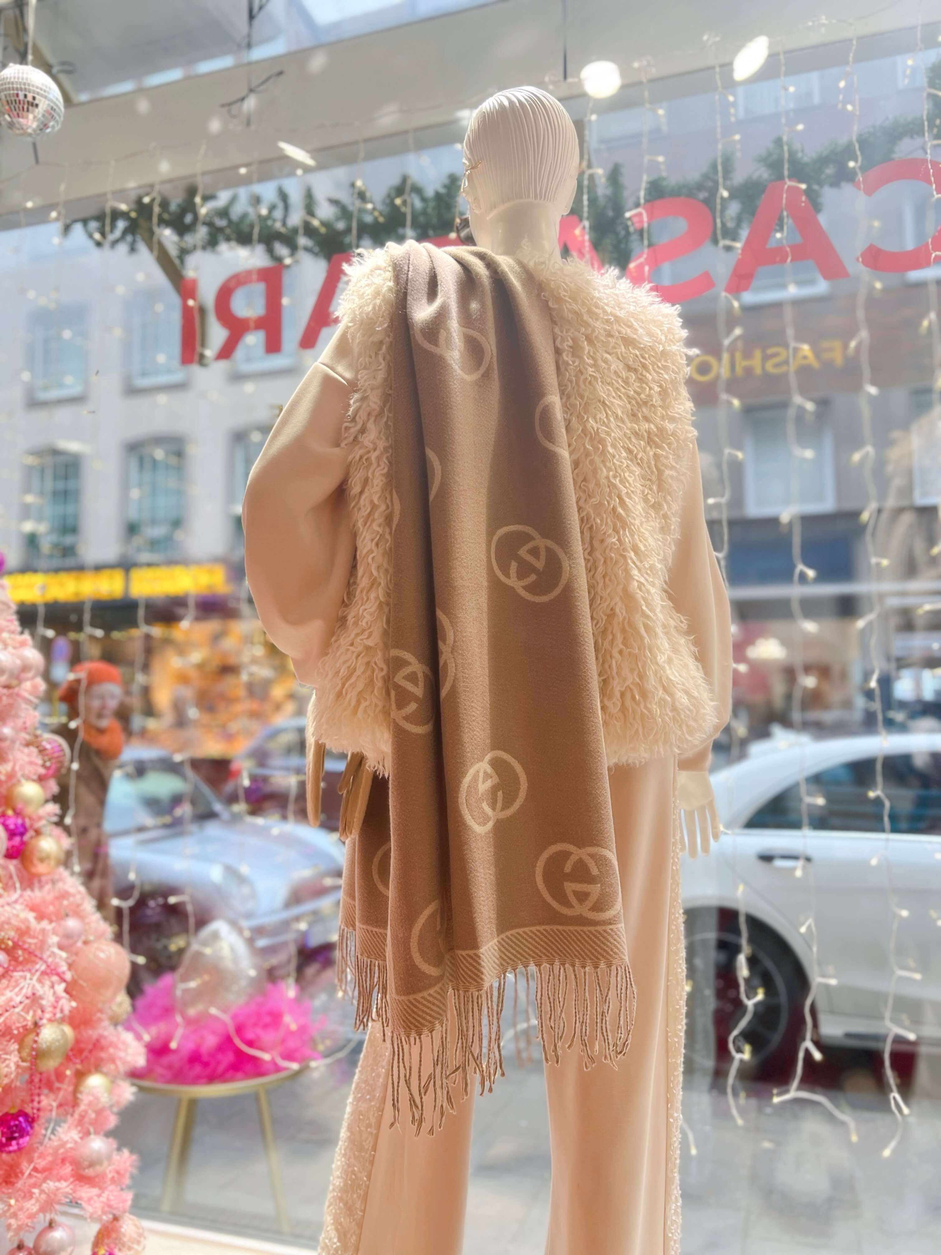 Schaufensterpuppe trägt Schal in beige, Taupe Muster. Über die Schulter gelegt. In einer Boutique fotografiert.