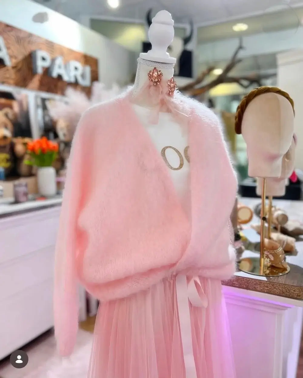 Rosa Kid-Mohair-Cardigan Rosé Cloud auf Schneiderbüste mit Wickeloptik und langen Ärmeln.“