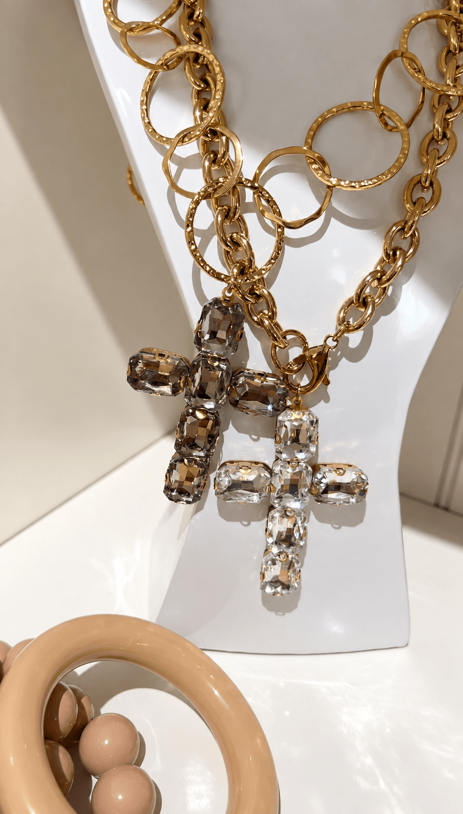 Goldfarbene CASAPARI Gliederkette aus Edelstahl mit großem Kreuzanhänger aus facettierten Kristallglassteinen in Smoky-Braun.
