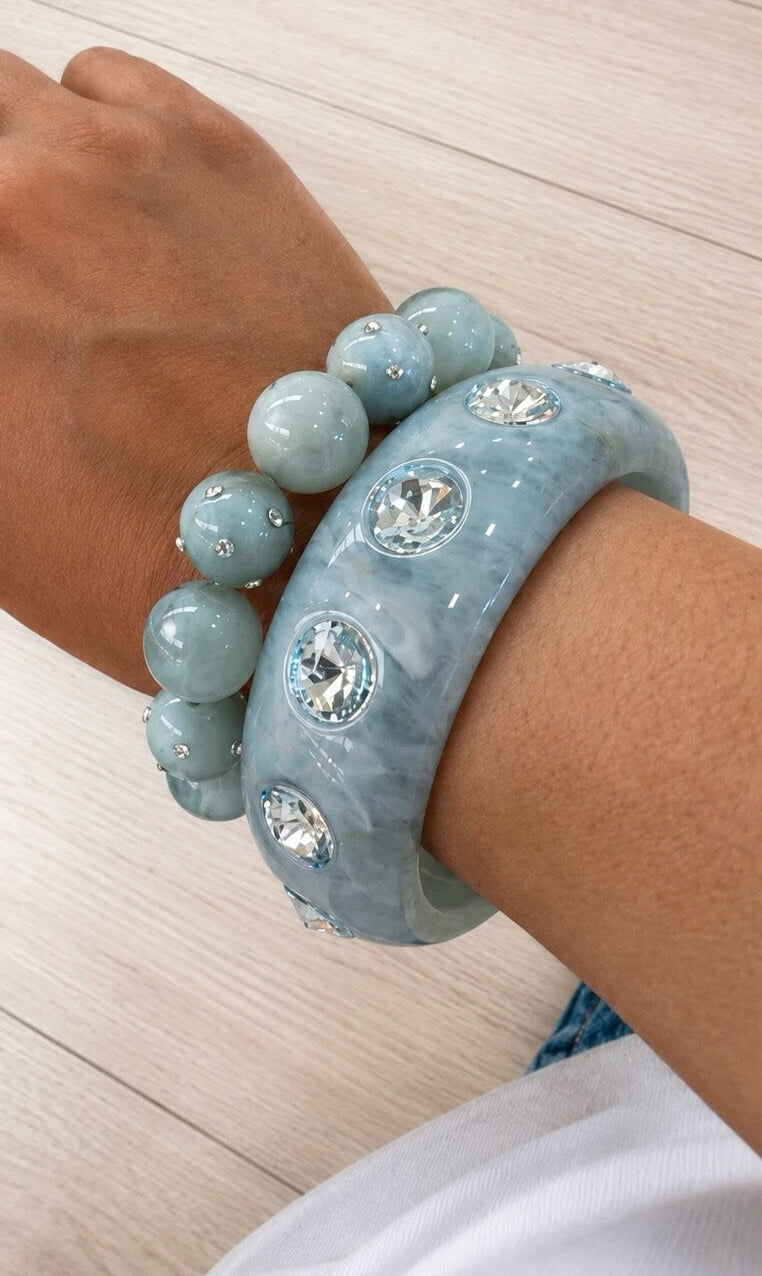 Hellblaues Schmuckset aus Perlenarmband und Armreif mit Kristallsteinen am Handgelenk getragen.