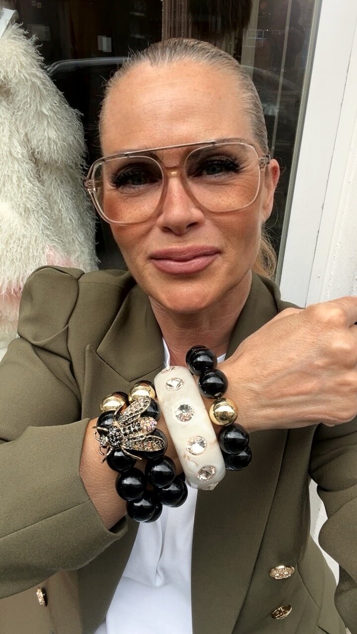 Frau Frau trägt mehrere Armbänder sie trägt einen grünen Bläser und hält es so in der Luft