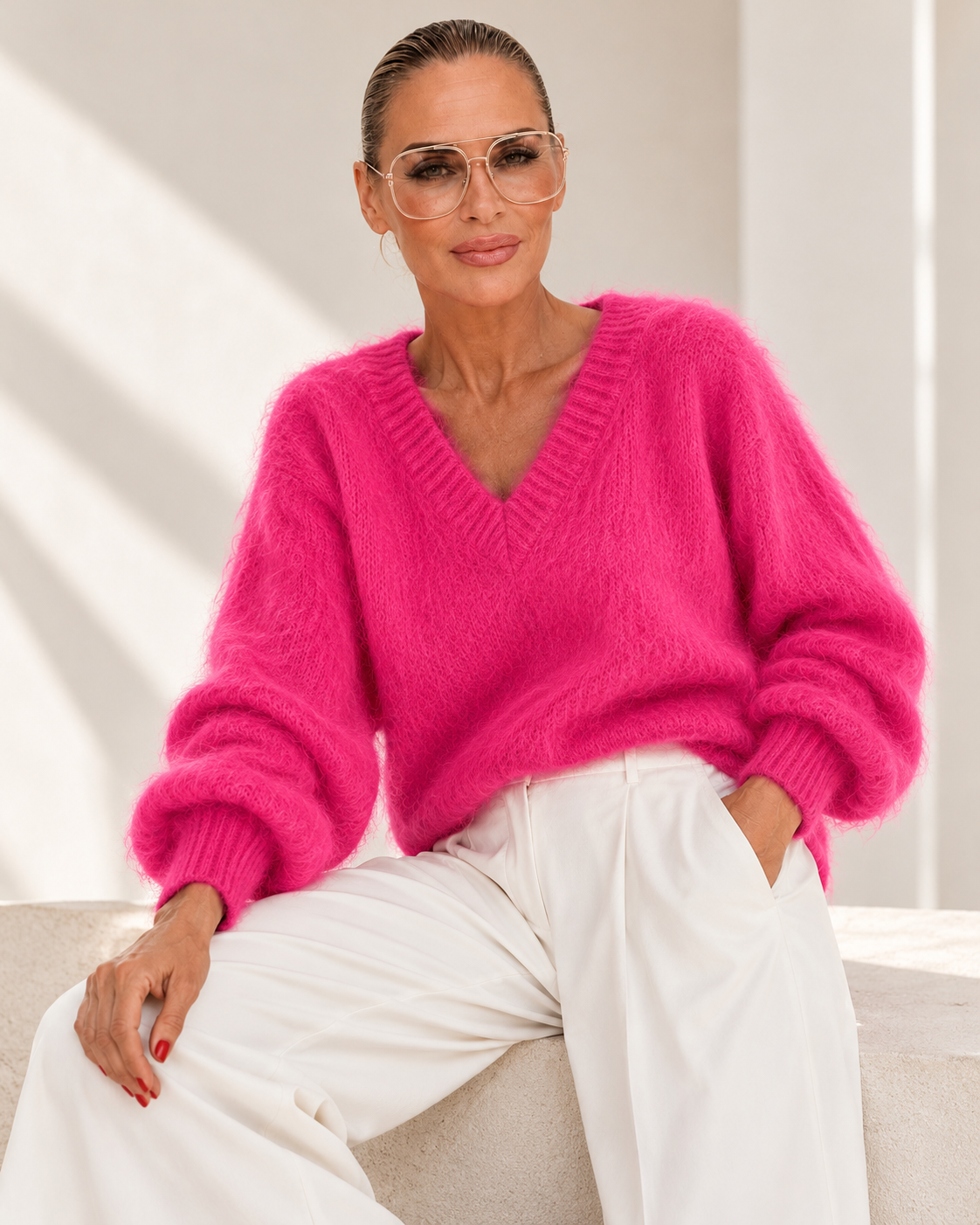 KI-generiertes Editorial: Model mit goldener Brille im Bubble Pink Kid Mohair Pullover mit V-Ausschnitt und weißer Marlenehose