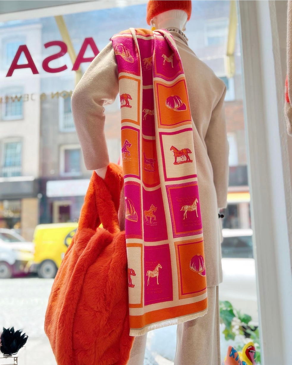 Schaufensterpuppe trägt Schal in pink, Orange und Beige mit Karomuster. Über die Schulter gelegt.