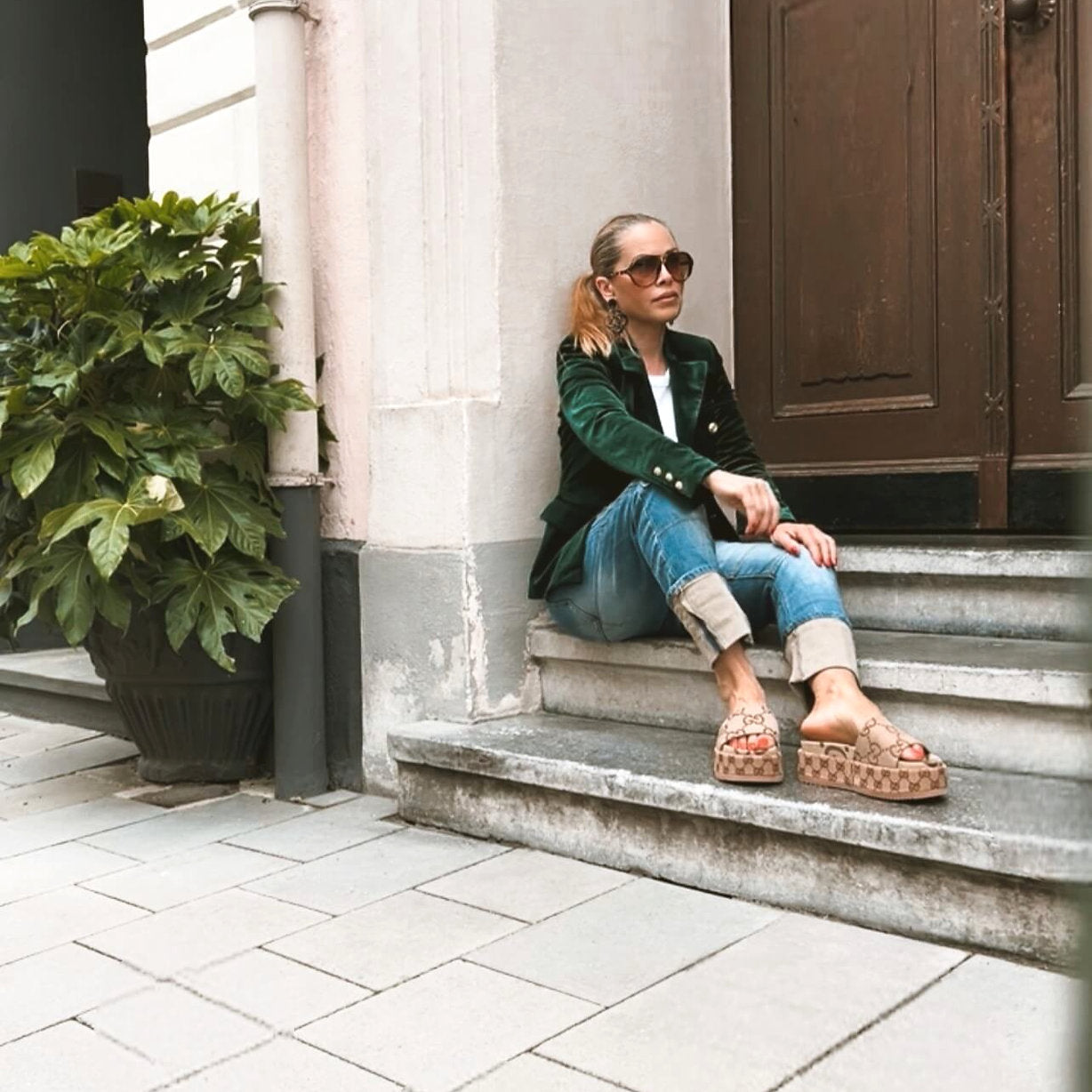 Model sitzt seitlich im CASAPARI® Samtblazer in Tannengrün. Weicher Samt, goldene Knöpfe, taillierter Schnitt, stilvoller Look.