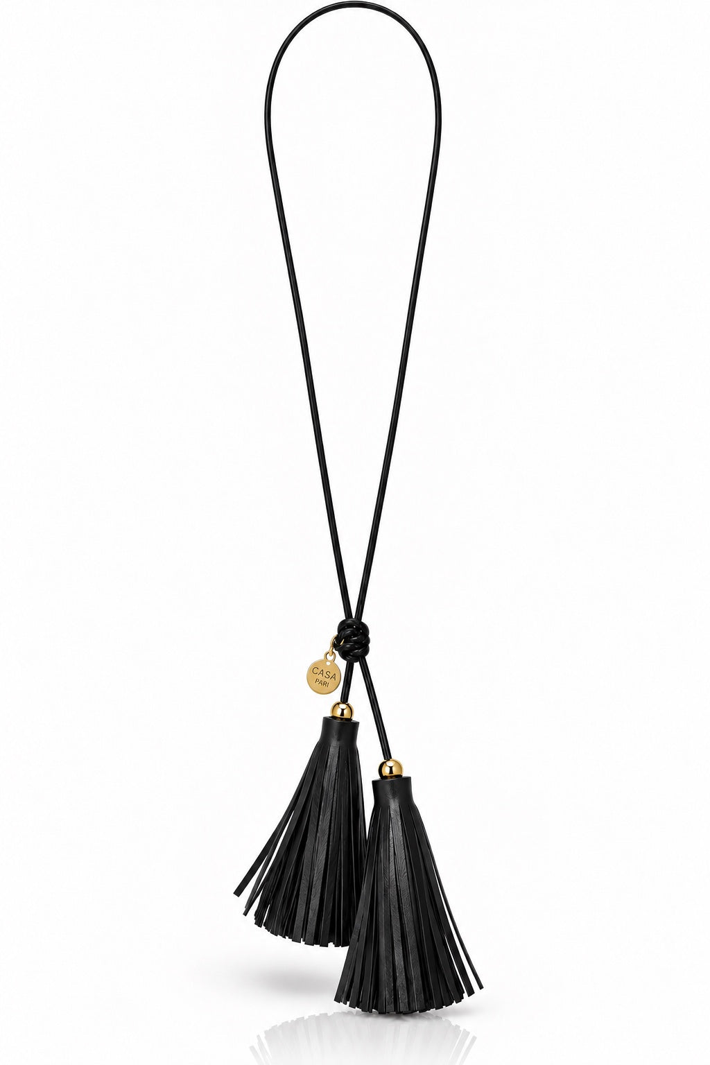 Lange schwarze Lederkette mit zwei Quasten, goldfarbenen Kugeln und Casa Pari Logoanhänger auf hellem Hintergrund