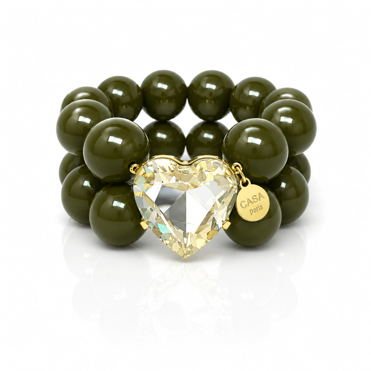 Armband aus glänzenden olivgrünen Resin-Perlen mit großem facettiertem Kristallherz in Champagner-Optik, goldfarbener Fassung und rundem Casapari-Anhänger auf weißem Hintergrund.