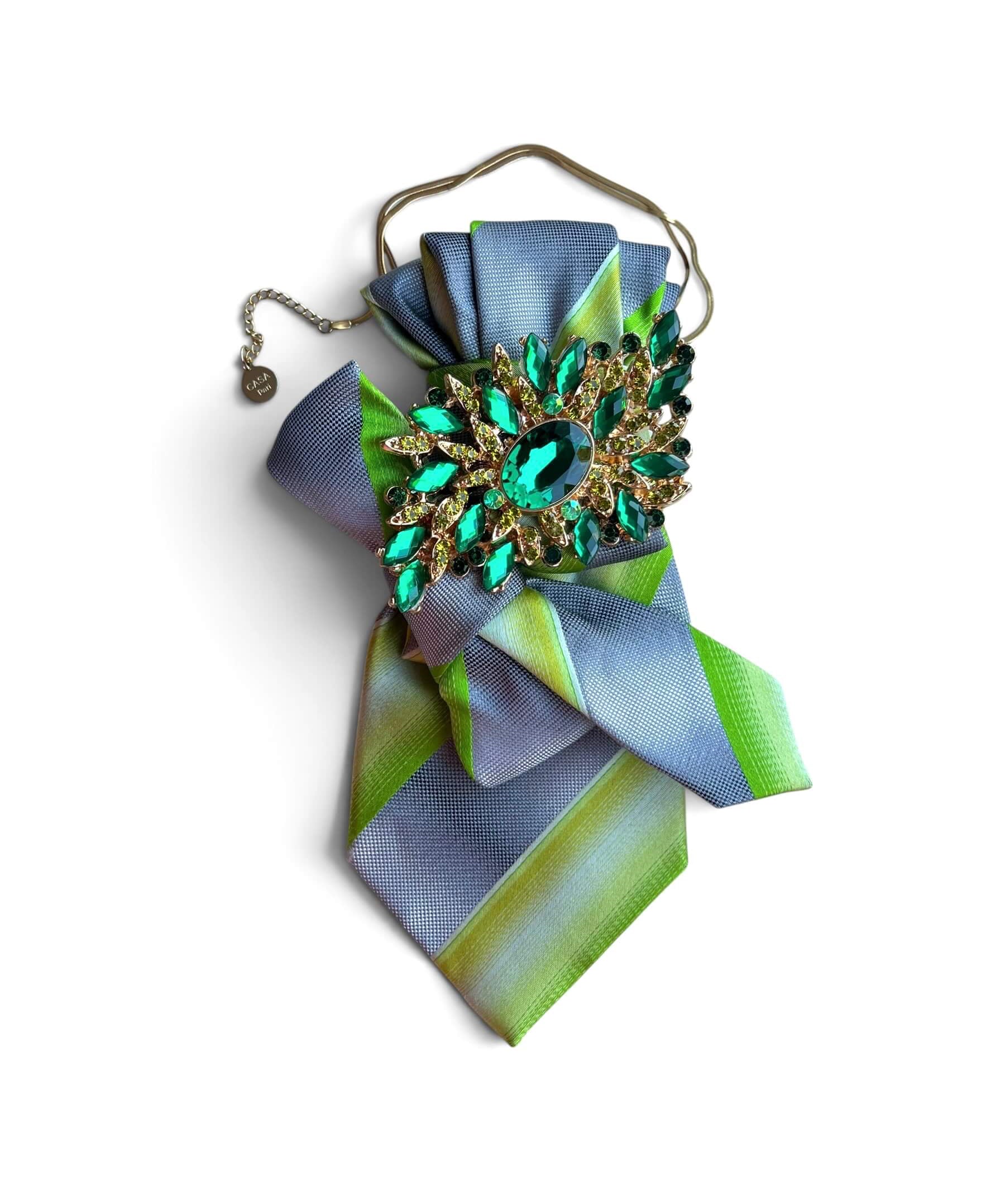 Statement-Krawatte aus Vintage-Seide in Hellblau und Grün mit Schleife sowie großer grüner Schmuckbrosche an goldfarbener Kette.