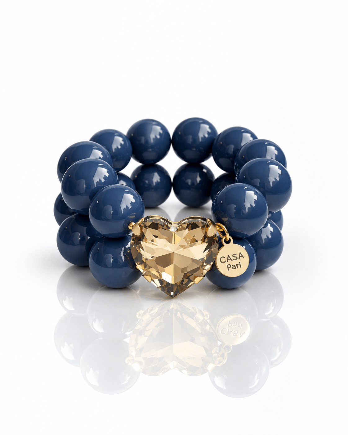 Casa Pari Crystal Heart Armband Denim Smoke mit großen blauen Perlen, champagnerfarbenem Kristallherz und goldenem Logo-Anhänger