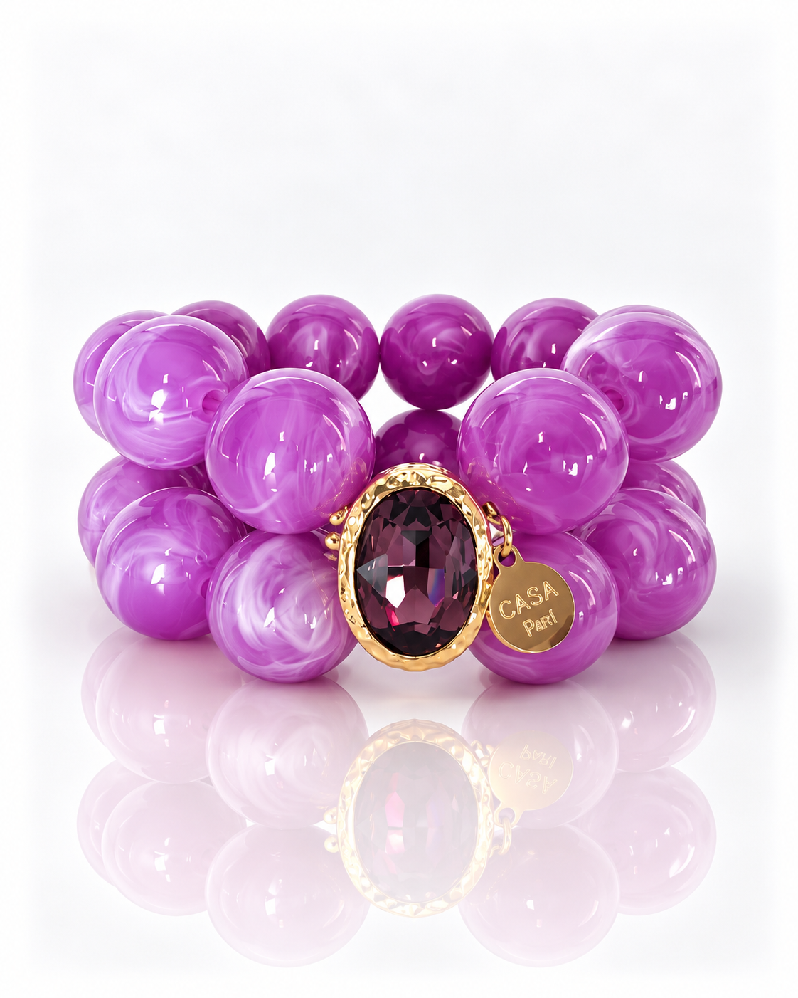 Crystal Purple – zweireihiges Perlenarmband mit facettiertem Kristall in goldfarbener Fassung und Casa Pari Anhänger auf weißem Hintergrund.