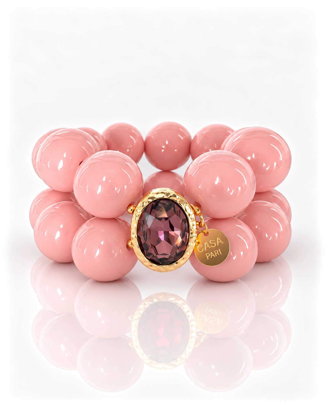 Crystal Rosé – zweireihiges Perlenarmband mit facettiertem Kristall in goldfarbener Fassung und Casa Pari Anhänger auf weißem Hintergrund.