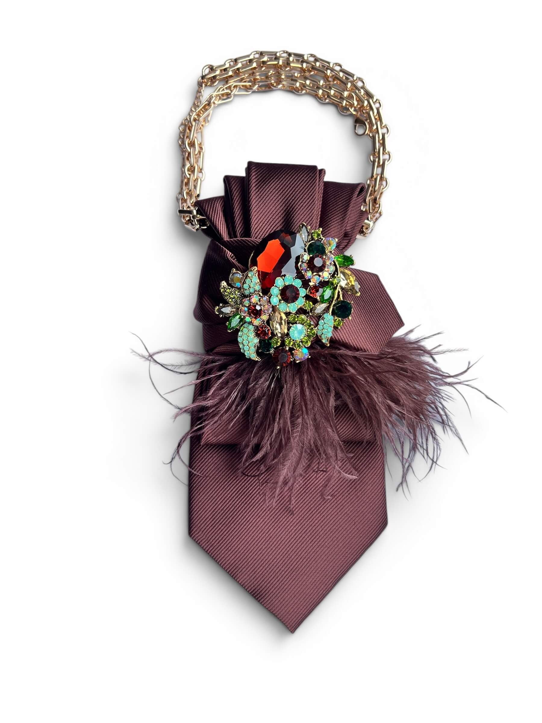 Vintage-Krawatte in dunklem Pflaumenton mit Schmuckbrosche aus bunten Steinen, Federdetail und goldfarbener Kette.