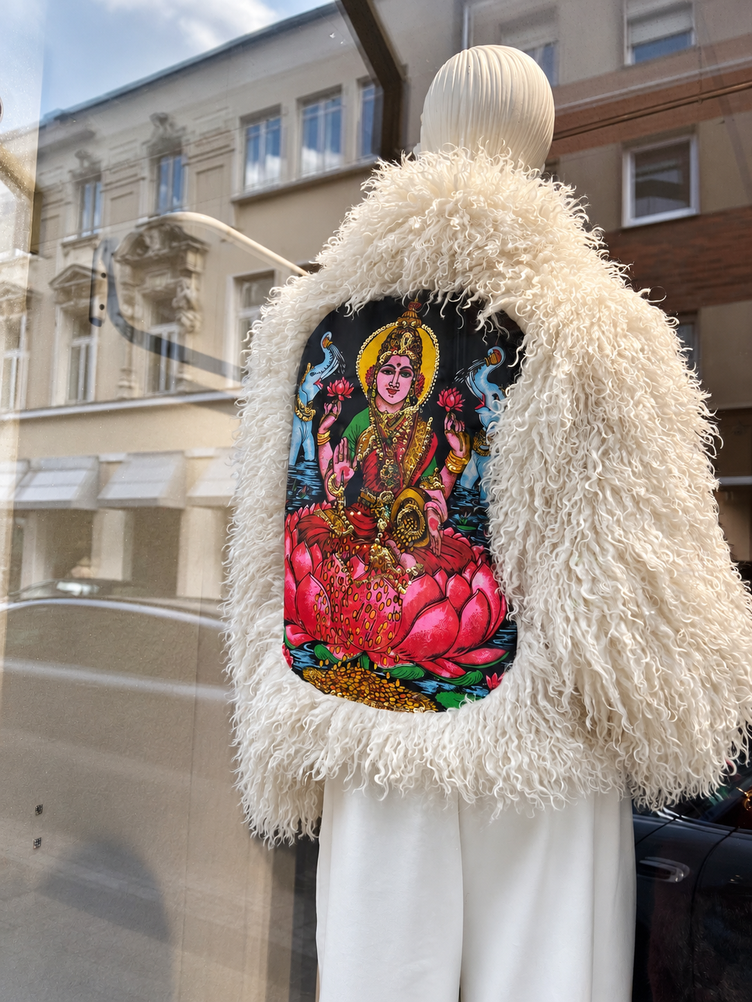 Cremefarbene Fluffy Jacket mit farbigem Rückenmotiv im Schaufenster