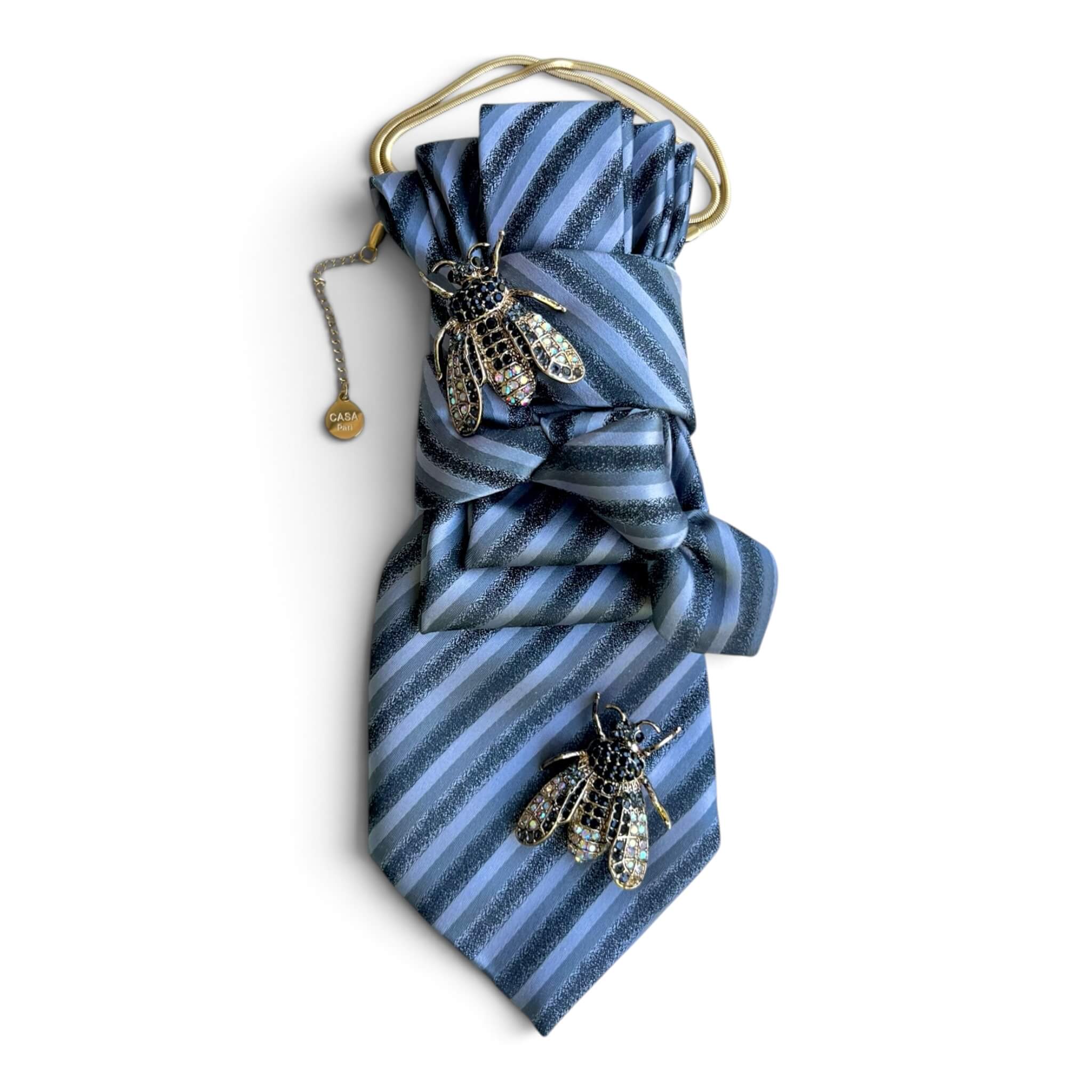 Blau gestreifte CASAPARI Seidenkrawatte mit goldfarbener Kette und zwei funkelnden Bienenbroschen.