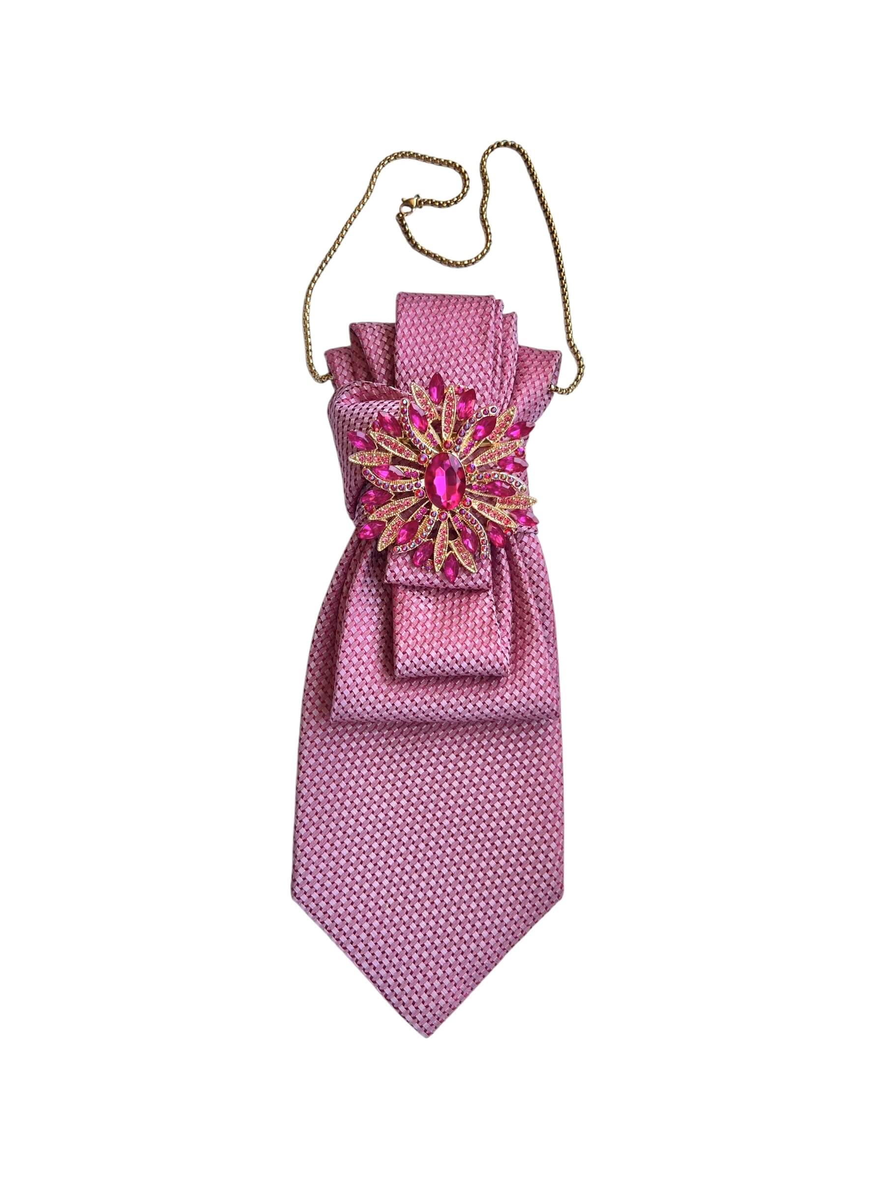 Seidenkrawatte in kräftigem Pink mit strukturierter Oberfläche, dekorativ gebunden, mit auffälliger pinkfarbener Brosche und feiner Kette auf hellem Hintergrund