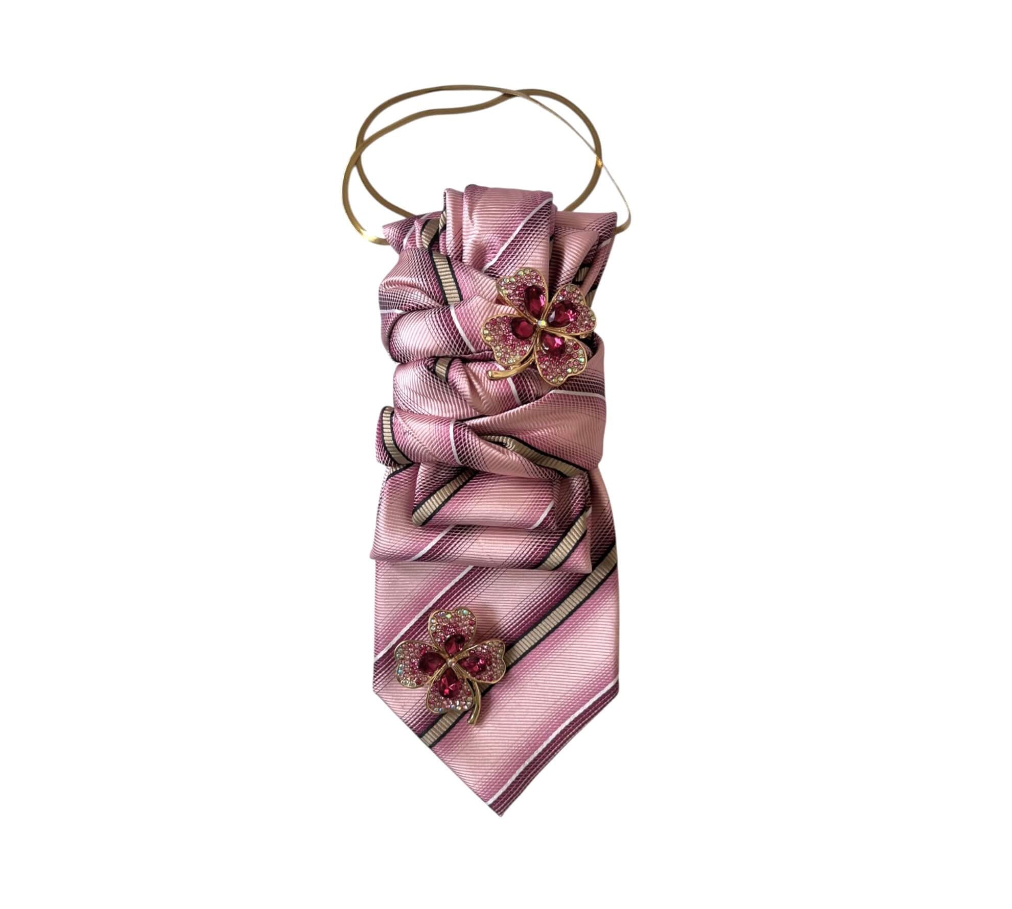 Roséfarbene Vintage-Krawatte mit diagonalem Streifenmuster, dekorativen Schmetterlingsbroschen in Pink und goldfarbenem Halsreif, freigestellt auf hellem Hintergrund.