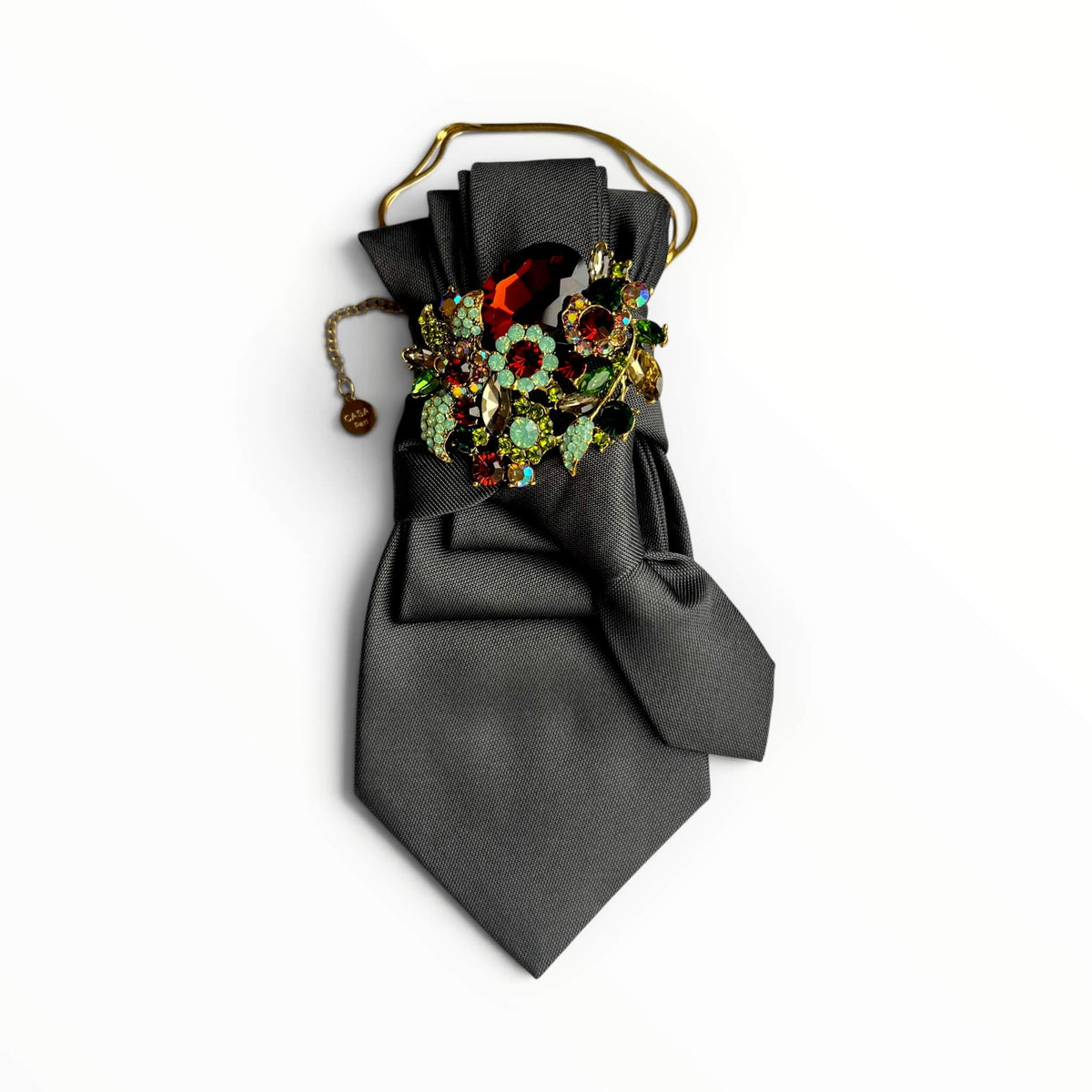 Graue Krawatte mit großer Schmuck,brosche und goldene Kette auf weißem Hintergrund fotografiert