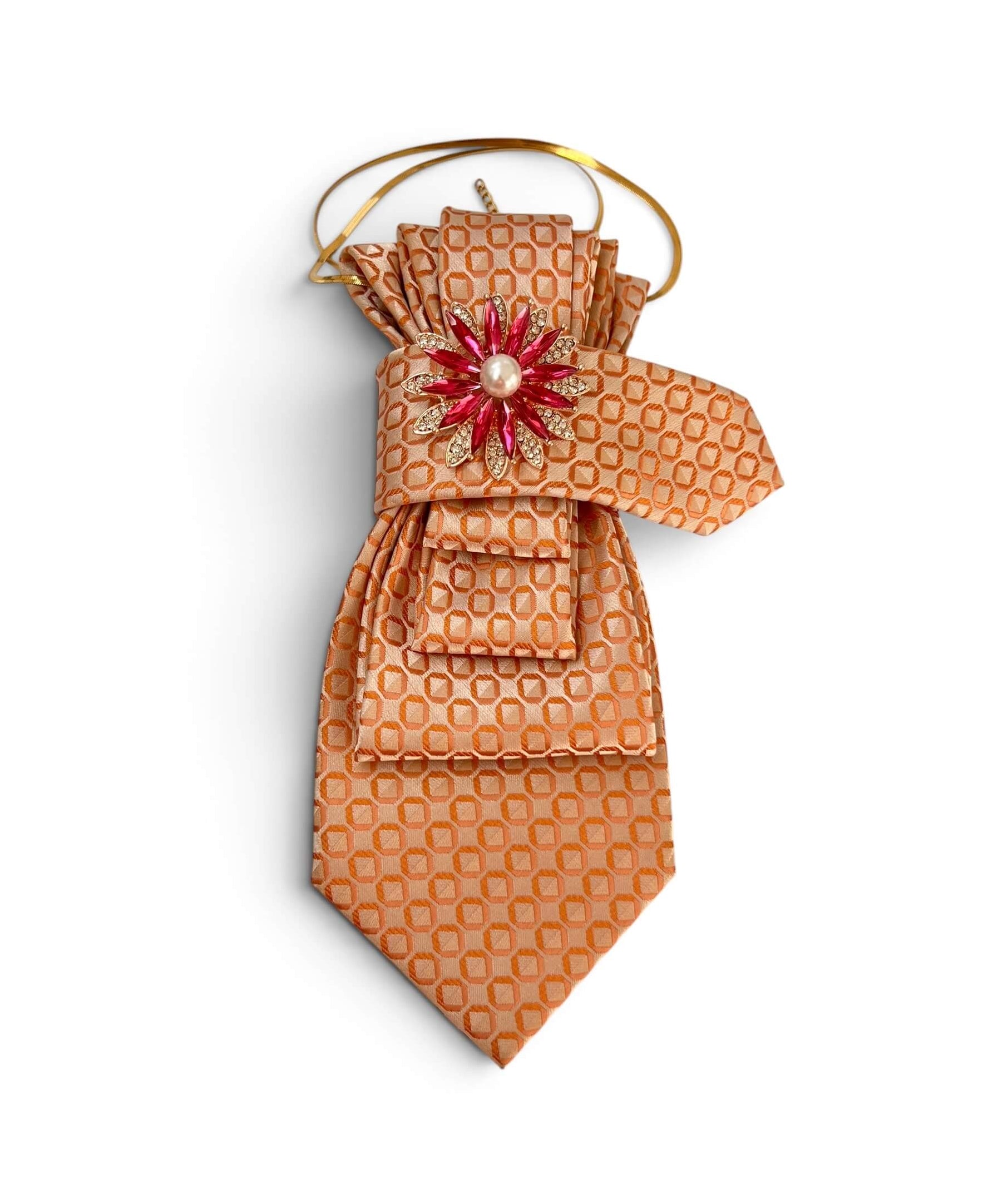Vintage-Krawatte in Apricot mit geometrischem Muster, dekorativer pink-goldfarbener Blumenbrosche mit Perlendetail und goldfarbener Kette auf hellem Hintergrund.