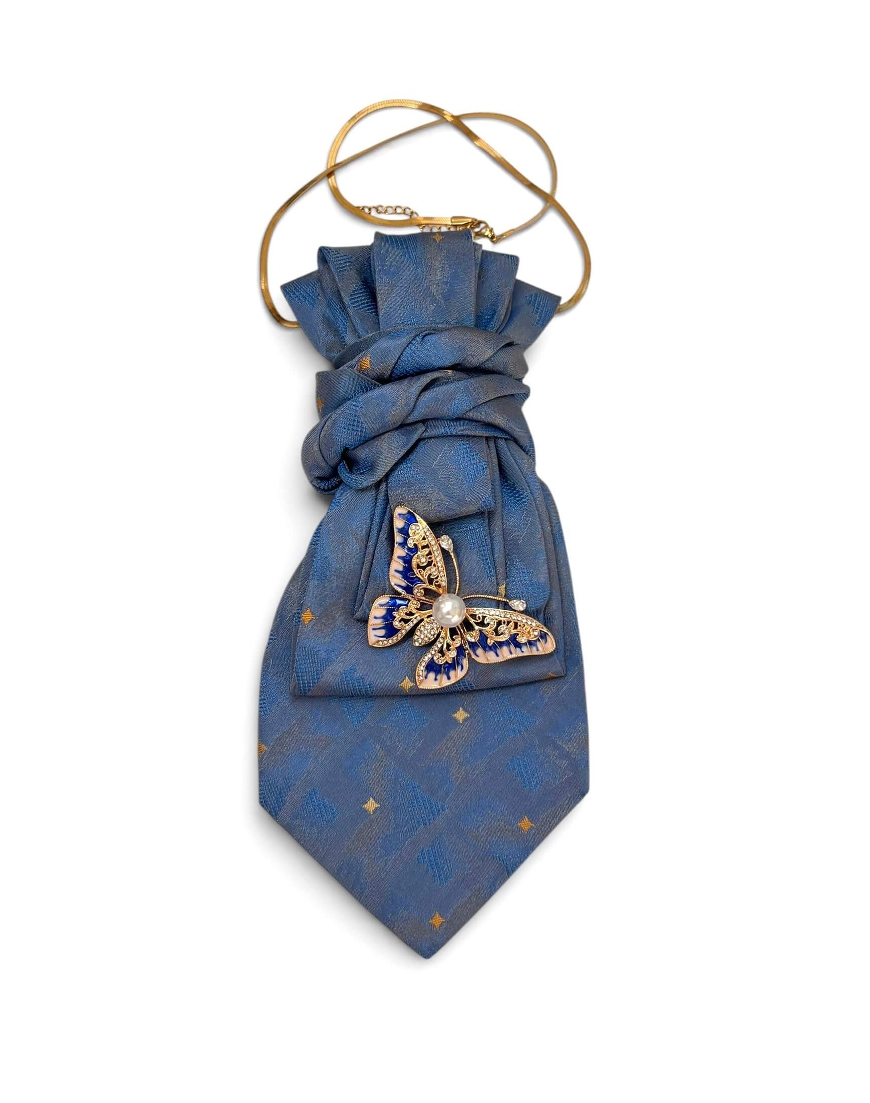 Vintage-Krawatte in hellem Blau mit dezentem Muster und goldfarbener Schmetterlingsbrosche mit blauen Details und Perlenelement.