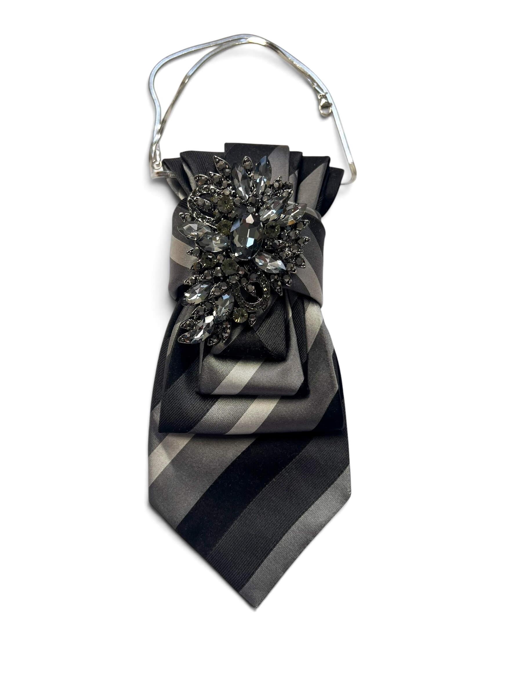Schwarze und graue Vintage-Krawatte mit breiten diagonalen Streifen, dekorativ drapiert mit dunkler Schmuckbrosche und silberfarbener Kette.