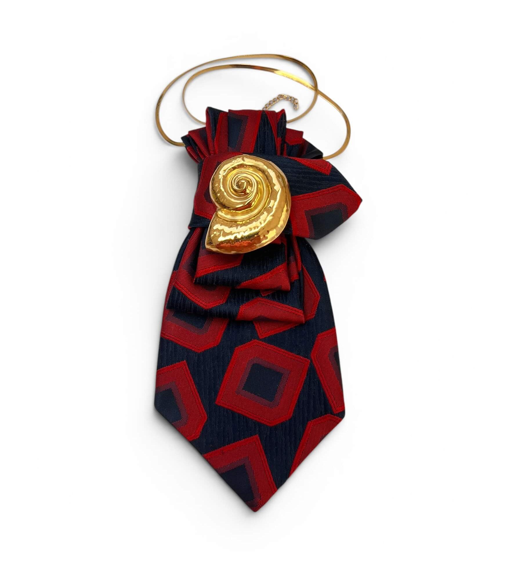 Vintage-Krawatte in Dunkelblau mit rotem geometrischem Muster, dekorativ gebunden mit großer goldfarbener spiralförmiger Schmuckapplikation.