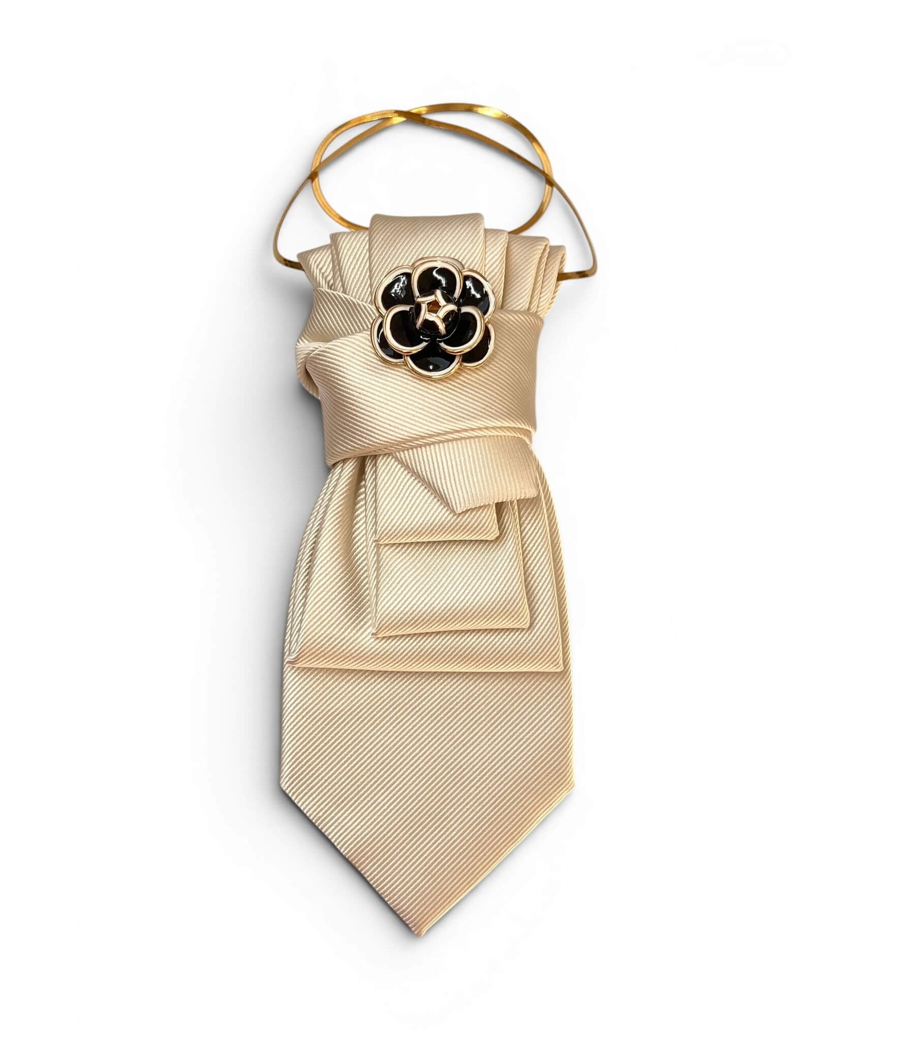 Vintage-Krawatte in hellem Cremebeige mit dekorativer Schleifenbindung, schwarzer Blumenbrosche und goldfarbener Kette auf hellem Hintergrund.
