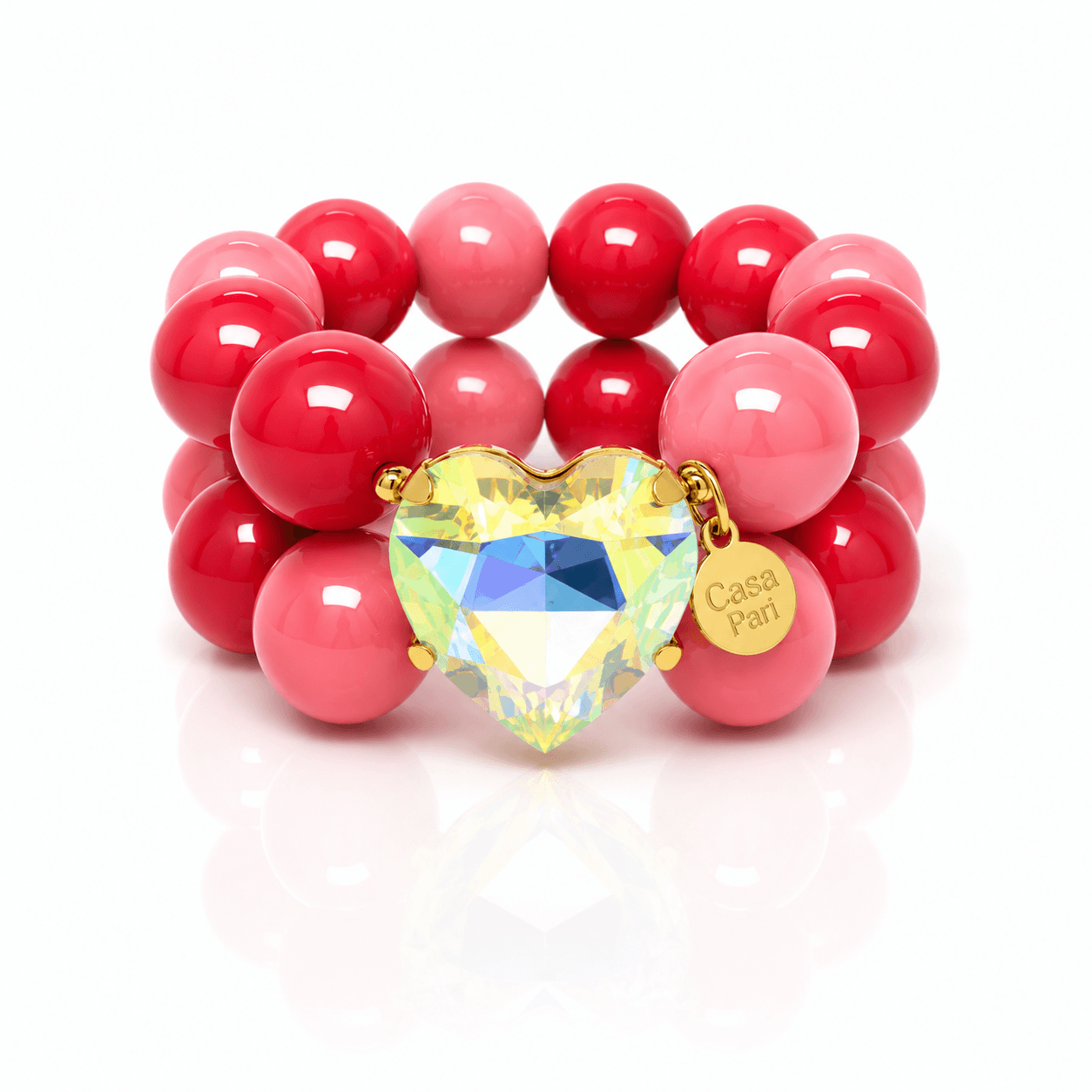 Crystal Heart Armband mit großen Perlen in Pink und Beerenrot sowie schillerndem Herzanhänger in Goldfassung auf hellem Hintergrund.