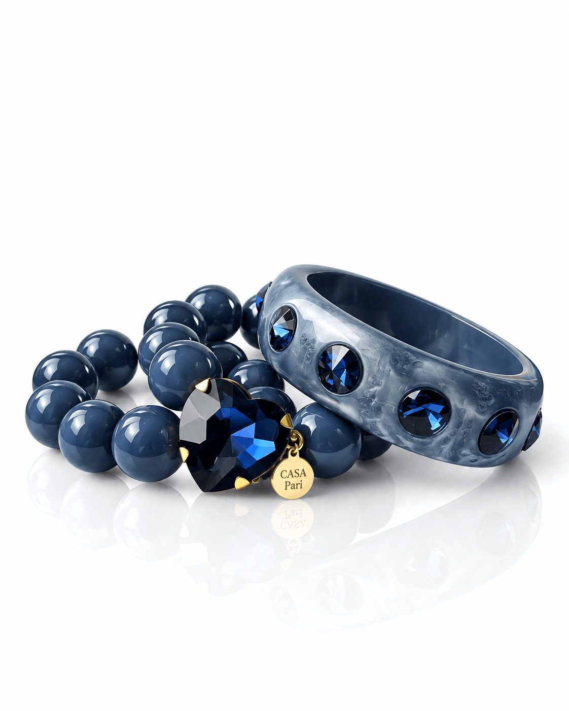 Crystal Heart Armband und breiter Bangle in Midnight Denim mit dunkelblauen Resin-Perlen, facettiertem Herzstein und blauen Schmucksteinen.