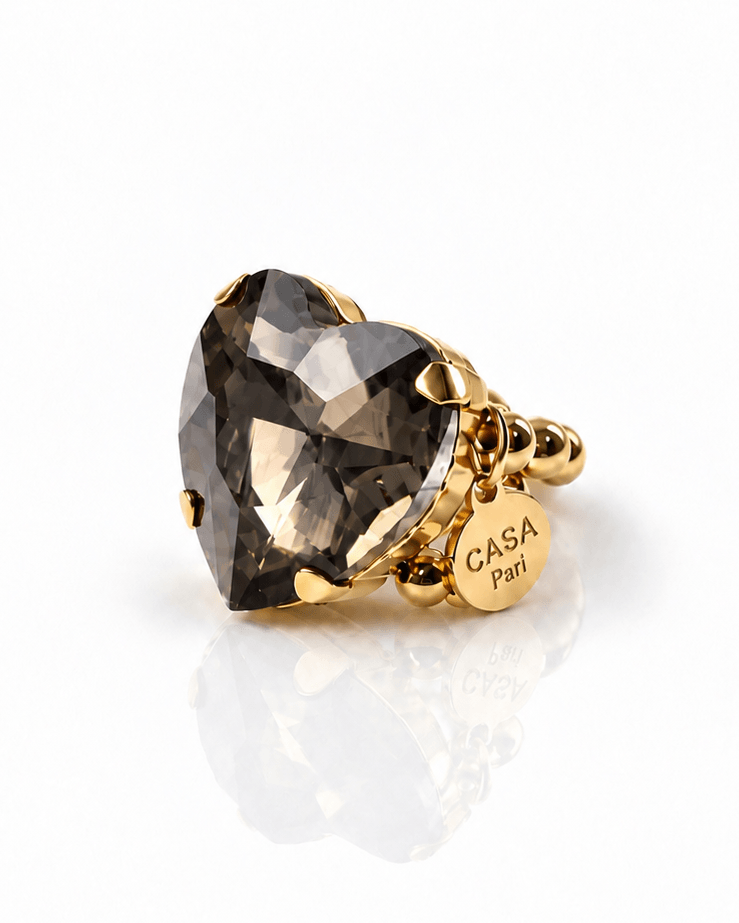 Goldfarbener Crystal Heart Ring mit großem facettiertem Herzstein in rauchigem Grau und elastischem Perlenring