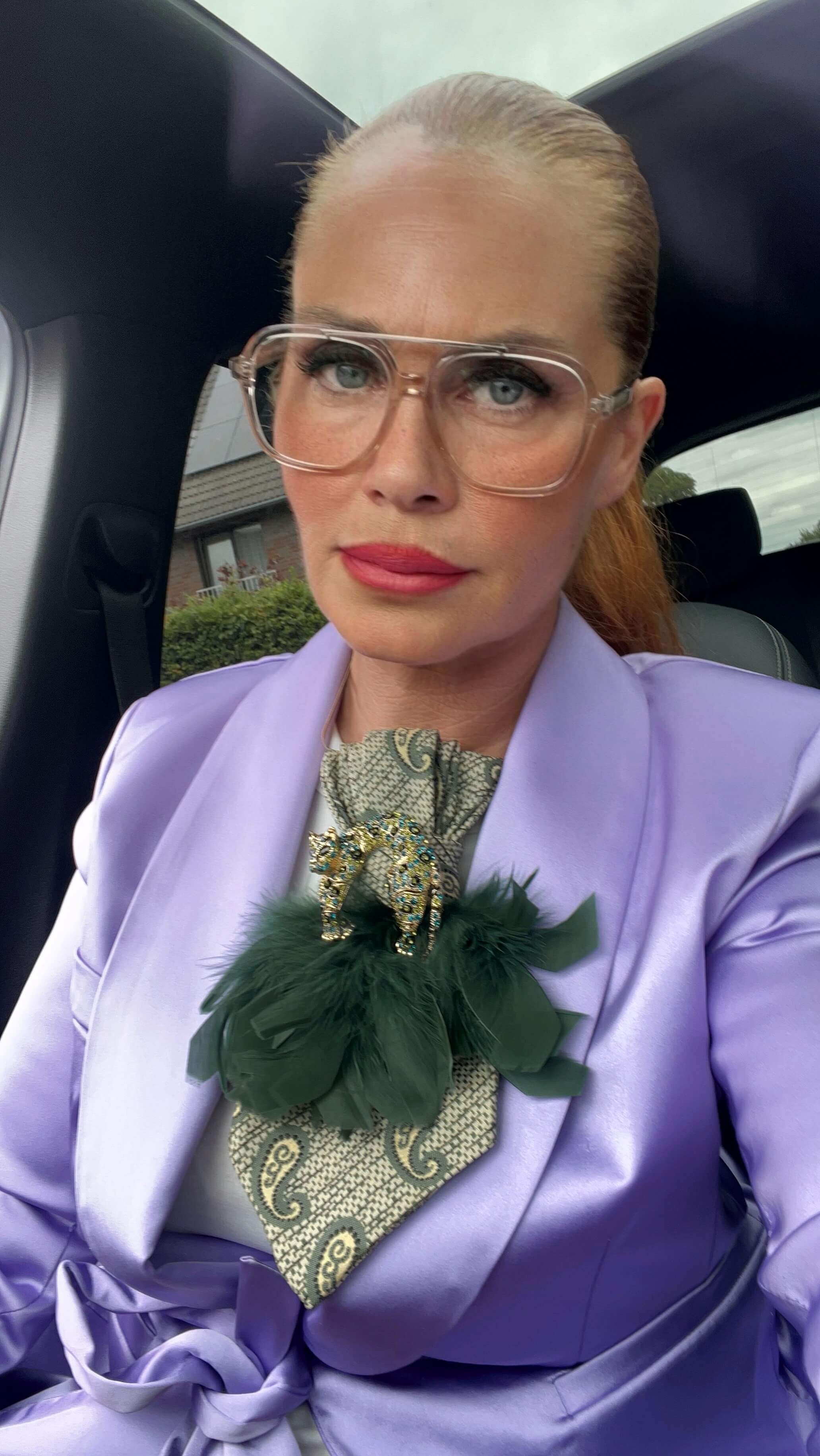 Model trägt die Vintage-Seidenkrawatte Sage Royale in Salbeigrün mit Paisleymuster, grünen Federn und Pantherbrosche zu einem fliederfarbenen Blazer.