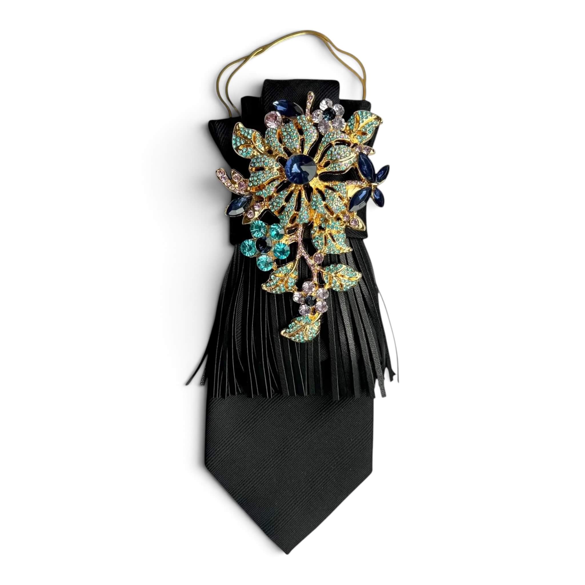 Schwarze Krawatte mit Leder,fransen und große, opulente Brosche mit Kette auf weißem Hintergrund fotografiert