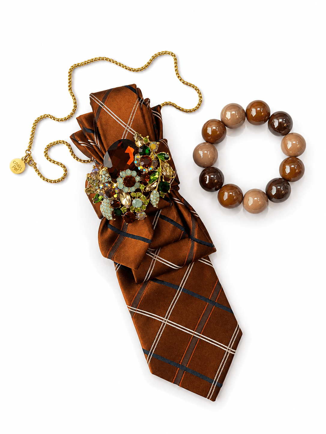 CASAPARI Perfect Match Affair Café Society mit braun gemusterter Krawatte, Schmuckbrosche und farblich abgestimmtem Perlenarmband.