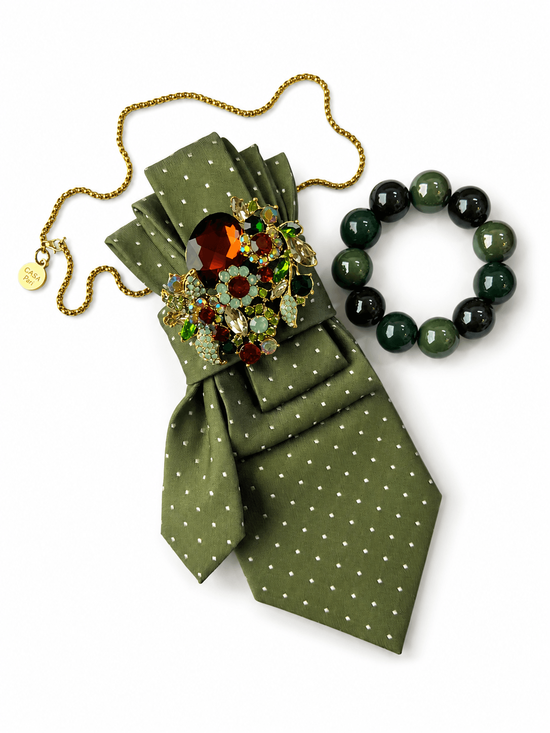 CASAPARI Perfect Match Affair Savoy Green mit olivgrüner Vintage-Krawatte, Schmuckbrosche, goldfarbener Kette und passendem Armband aus grünen Resinperlen.