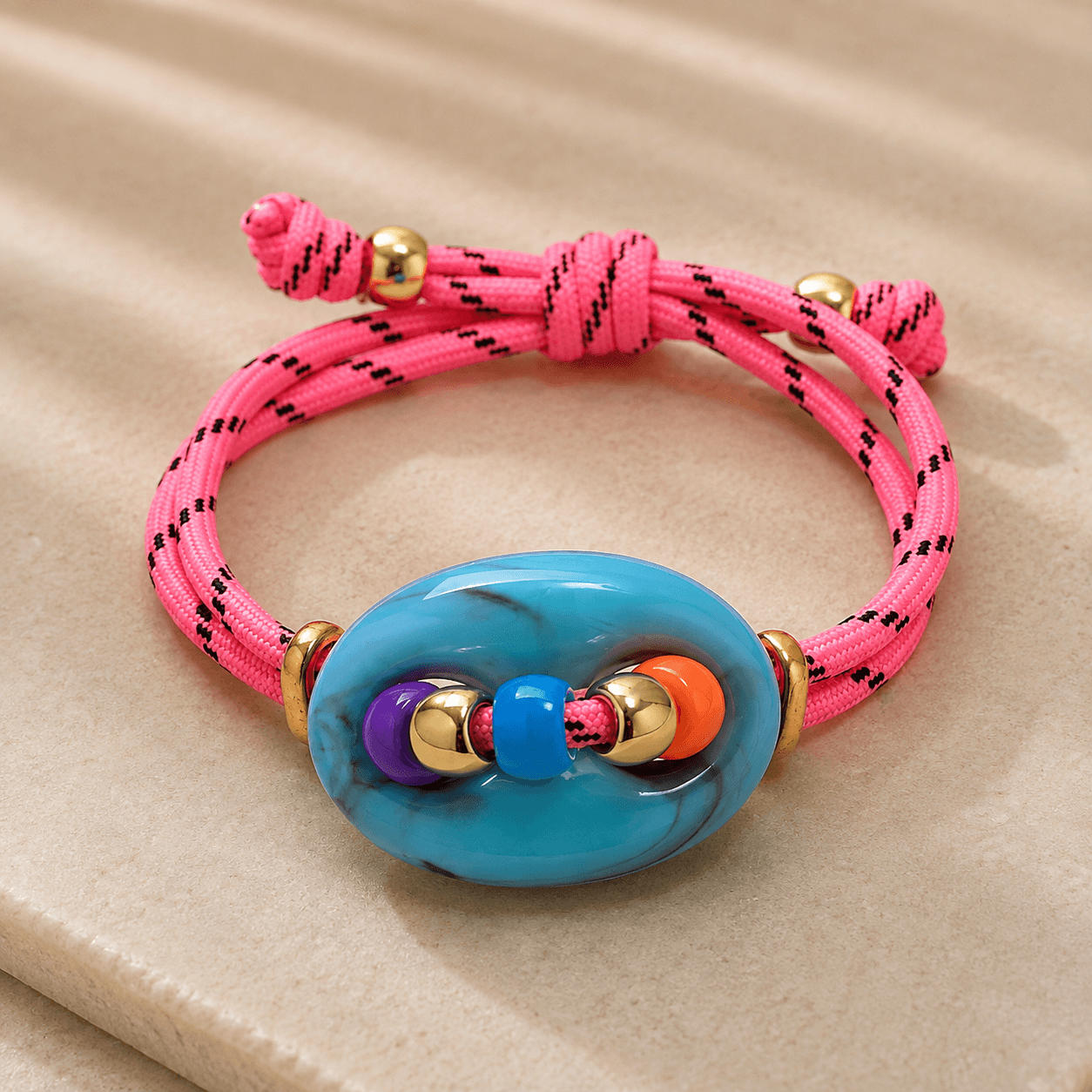 Pinkis Armband mit türkisen Schmuckelement liegt auf einer Steinplatte