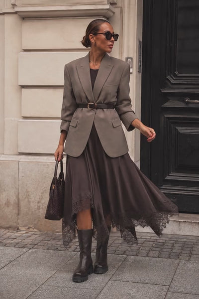 Frau trägt rock mit Spitze. Blazer mit Gürtel und eine Sonnenbrille und tasche dazu.