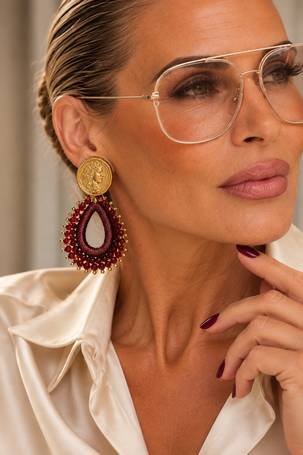 Model mit Roma Affair Burgundy Drops Ohrring und burgunderroten Nägeln