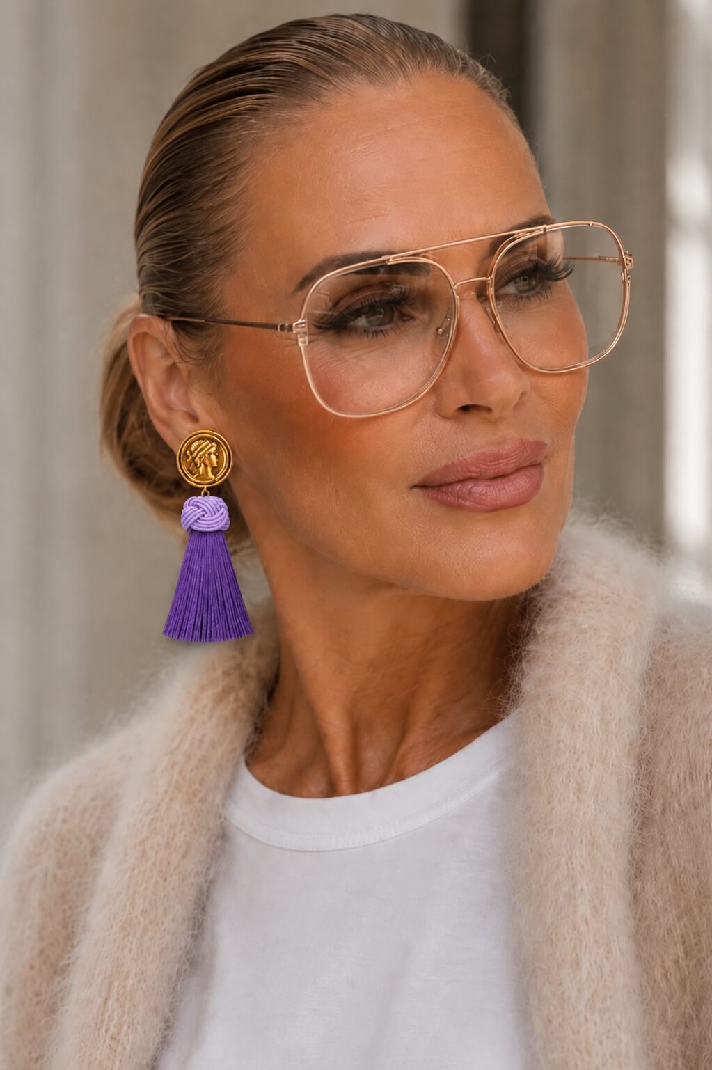 Frau trägt Roma Tassel Affair Ohrringe mit goldfarbener römischer Münze, fliederfarbenem Knotendetail und violetter Tassel