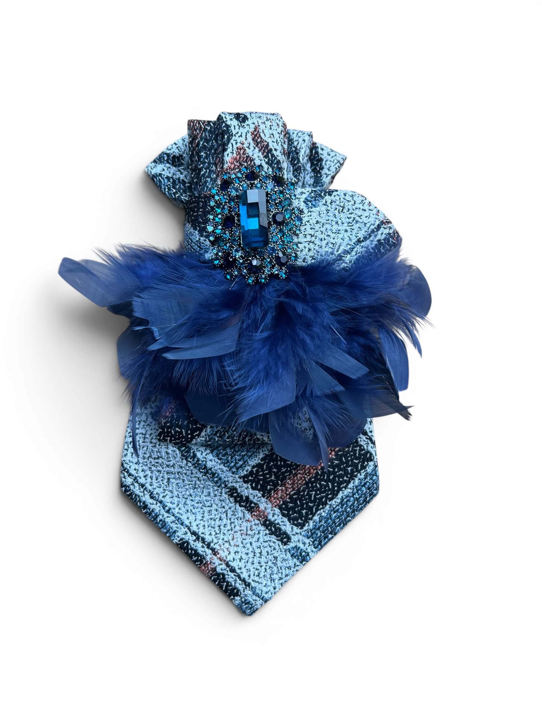 Blaue Vintage-Seidenkrawatte mit großer Schmuckbrosche und dunkelblauen Federn vor weißem Hintergrund.