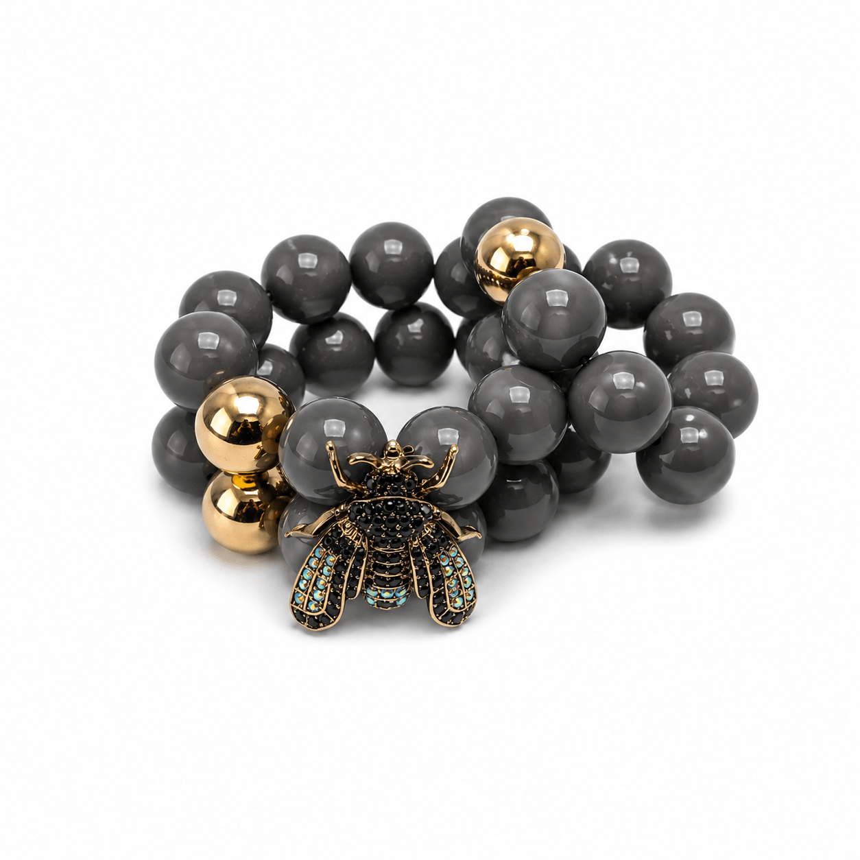 Doppelreihige Armband in schwarz mit Biene und ein passendes Armband im goldenen Perlen zu weißen Hintergrund fotografiert