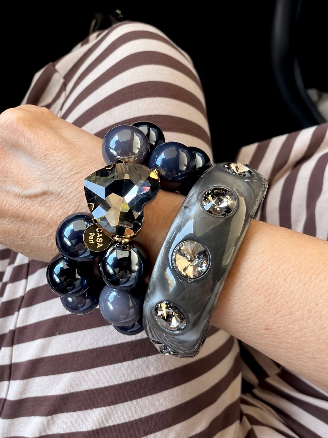 Doppel Reyes, graues Armband mit einem Kristallherz und ein Armreif in den grauam Handgelenk im Auto fotografiert